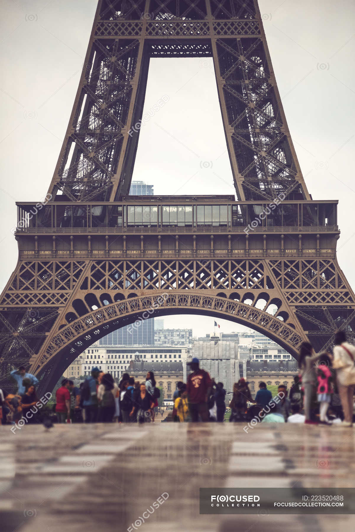 Basement of Eiffel Tower crowded by tourists on background of cityscape,  Paris, France — selective focus, gorgeous - Stock Photo | #223520488