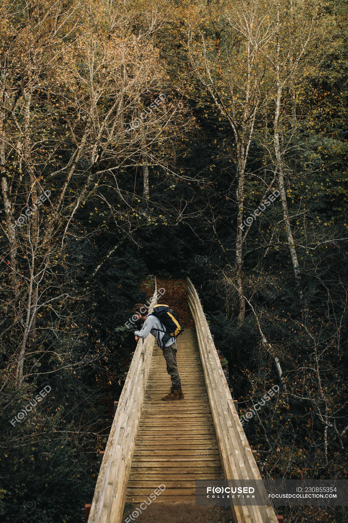 Young guy with backpack leaning on railing of ancient bridge near ...