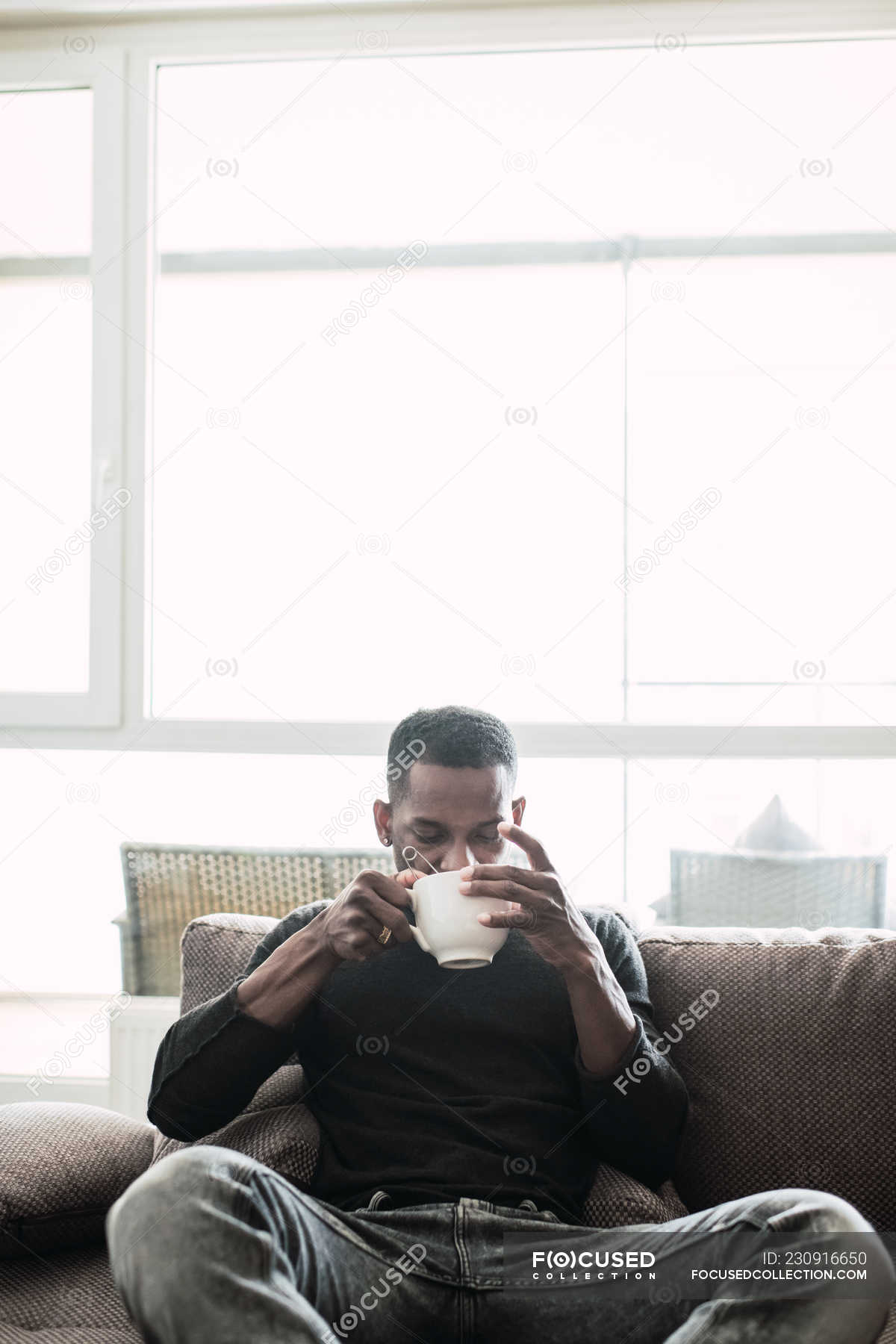 Pensive black man relaxing on sofa with coffee — handsome, interior ...