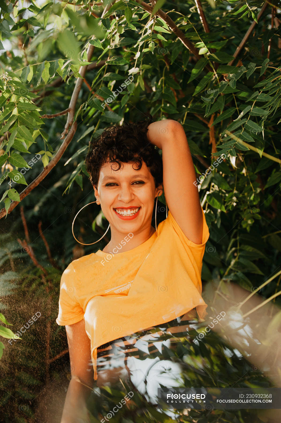  Portrait of smiling brunette with short hair standing in green ...