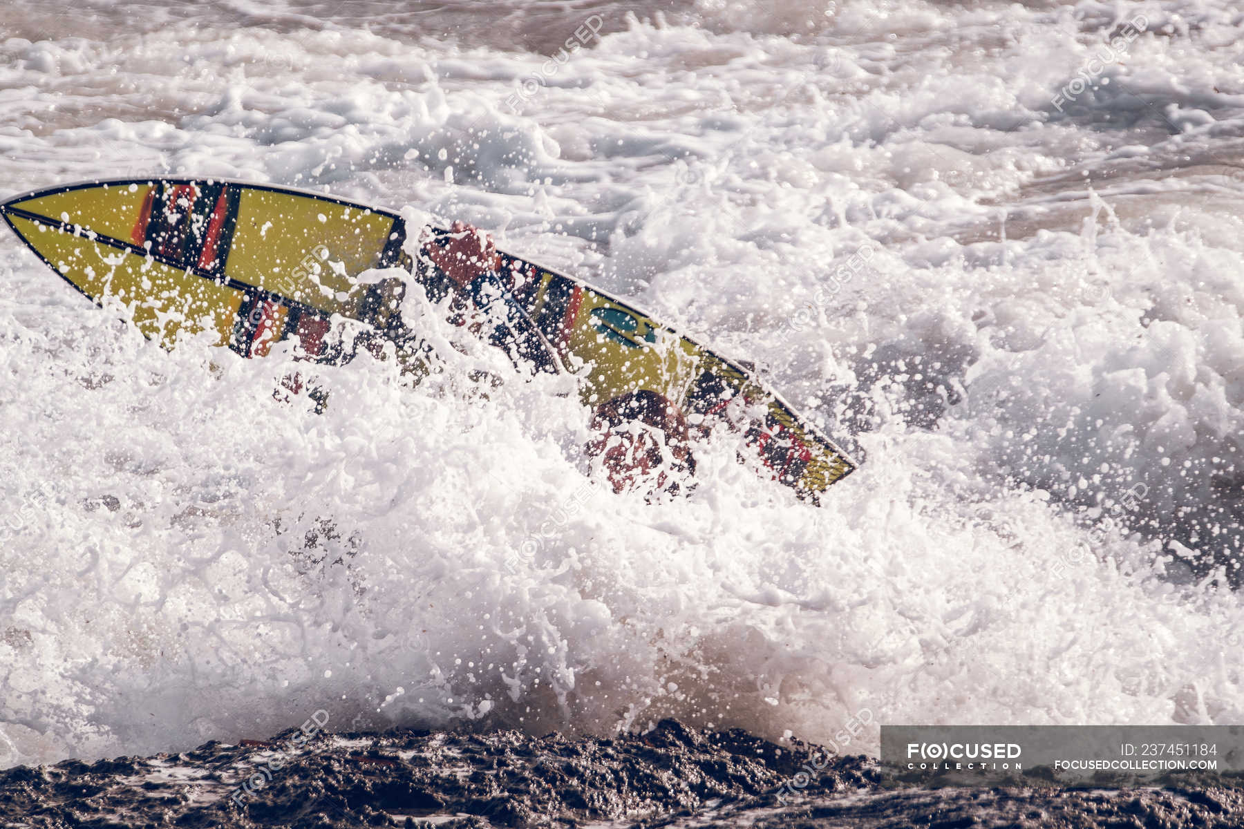 Bright surfboard in waves and splashes of sea near rocky shore — liquid ...