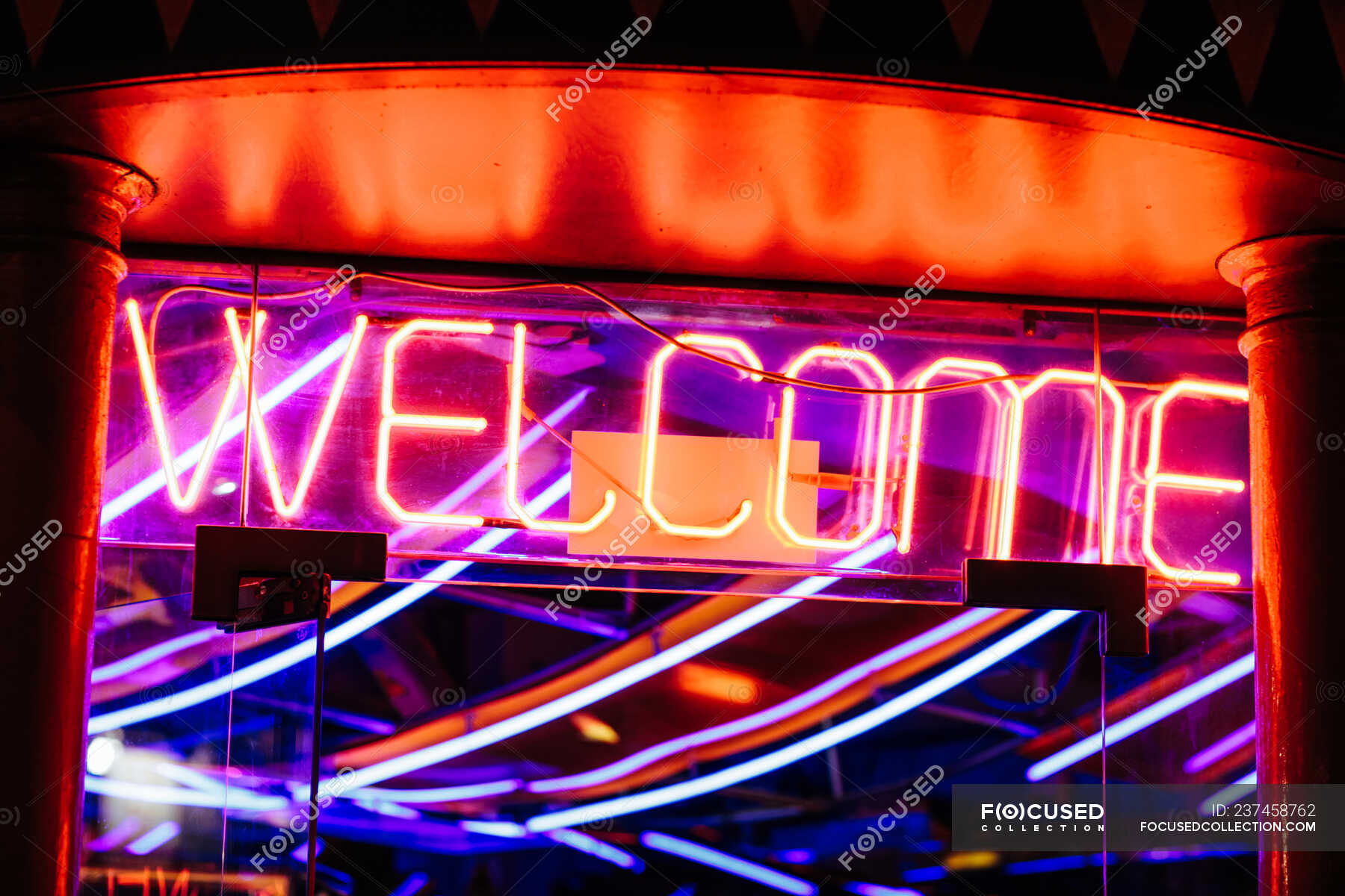 Bright welcome writing shining over entrance of modern club at night ...