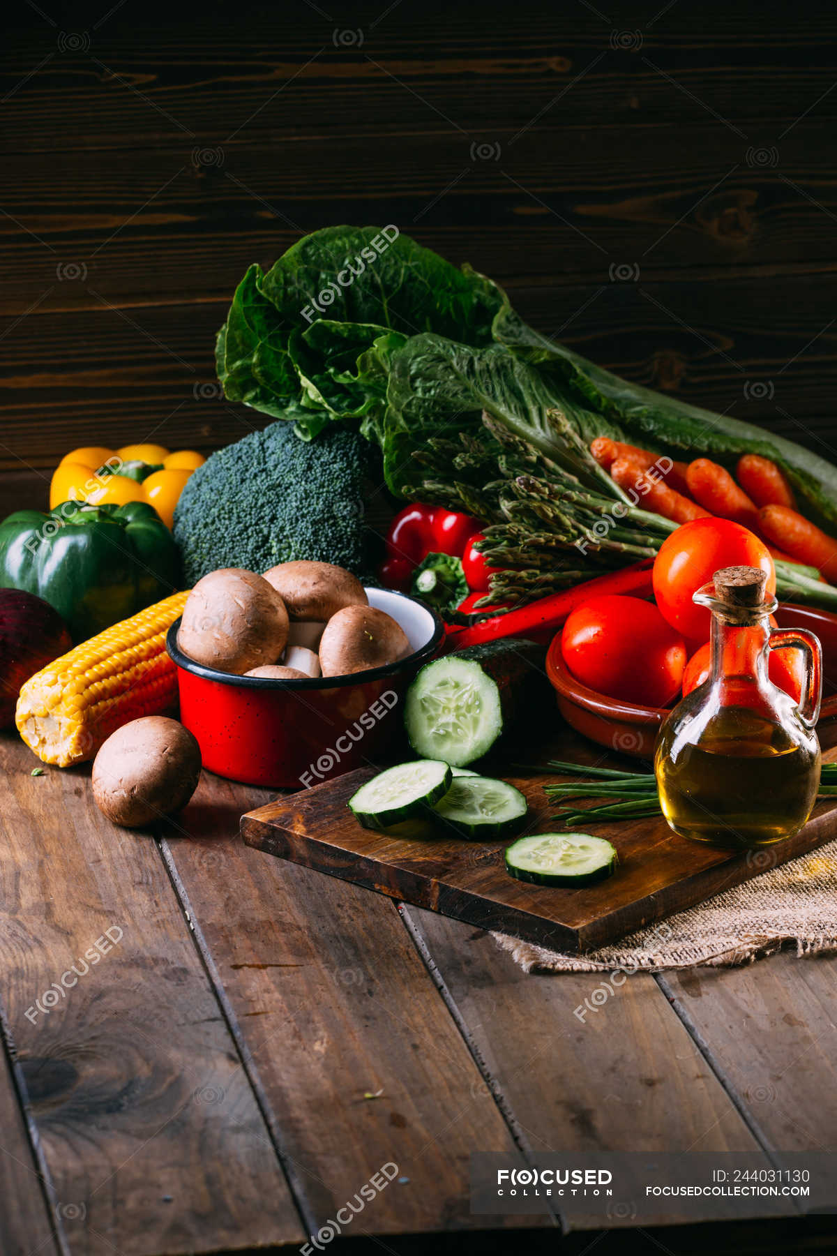 Assortment of fresh raw vegetables and utensils on wooden kitchen table