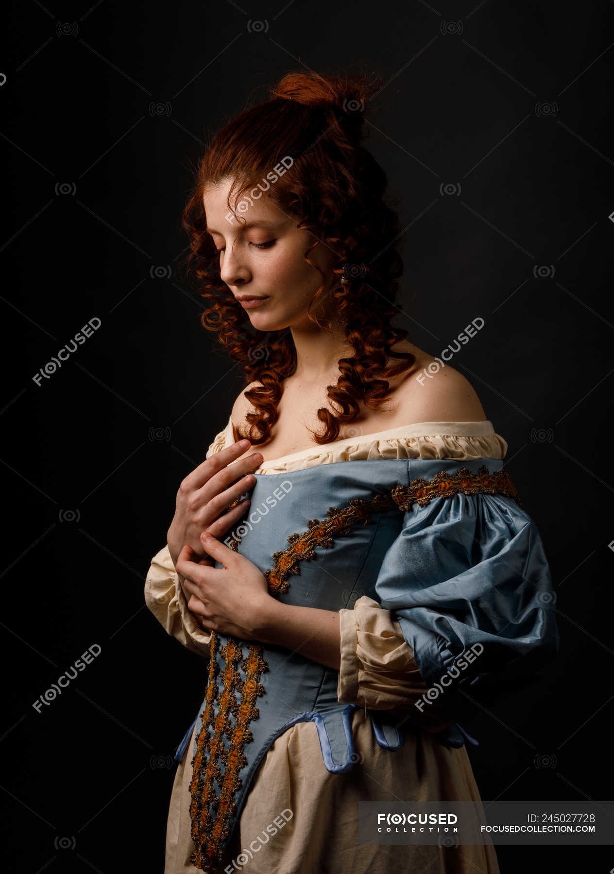 Beautiful woman in medieval clothing posing on black background ...