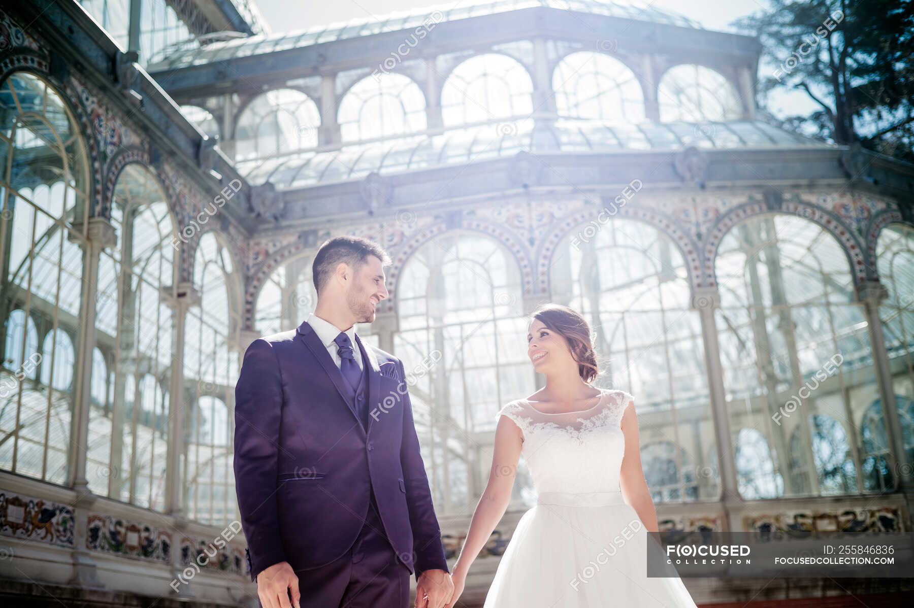 From below young elegant man holding on hands woman in wedding dress ...