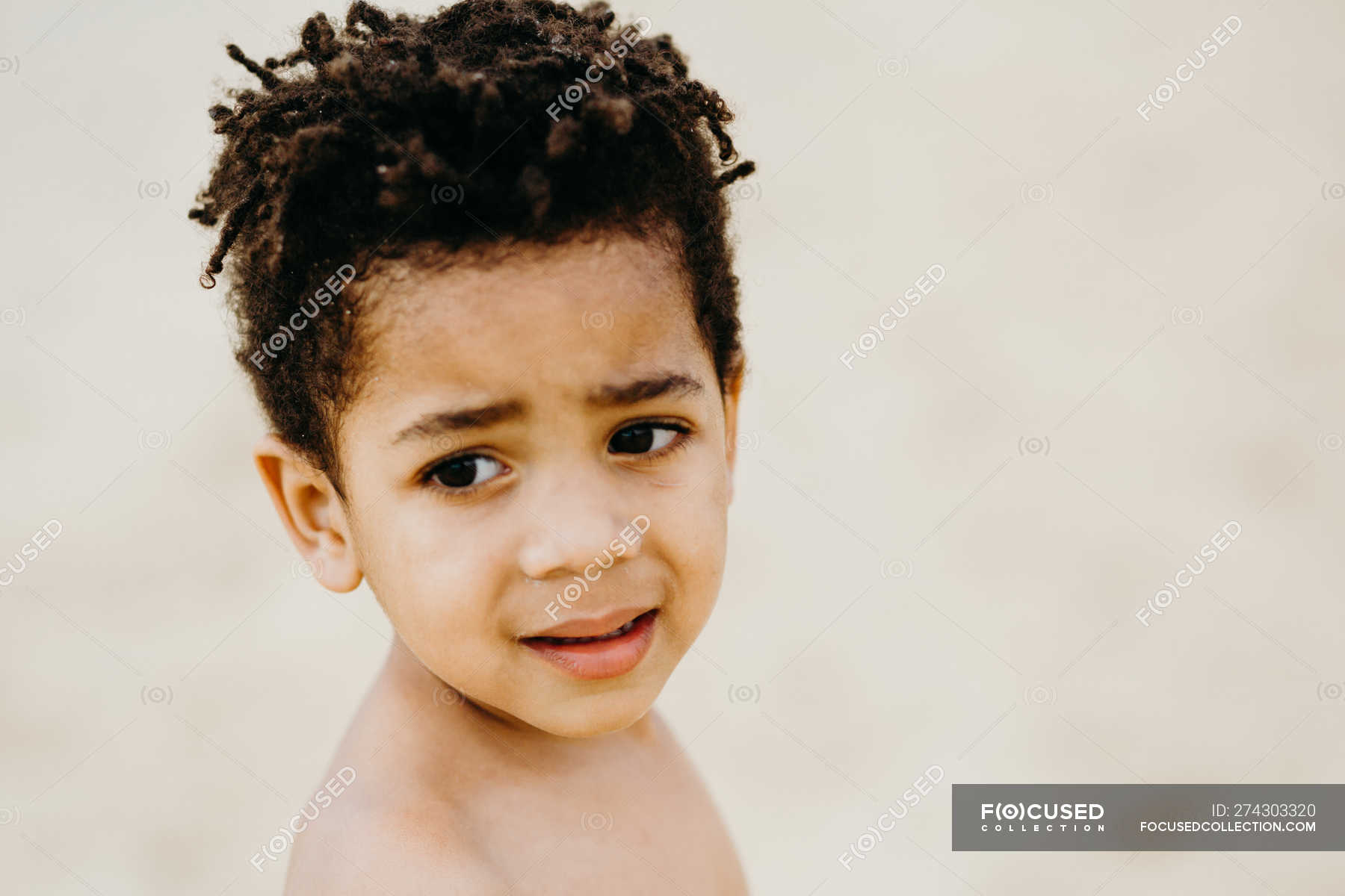 Side view of adorable shirtless African American boy looking away while ...