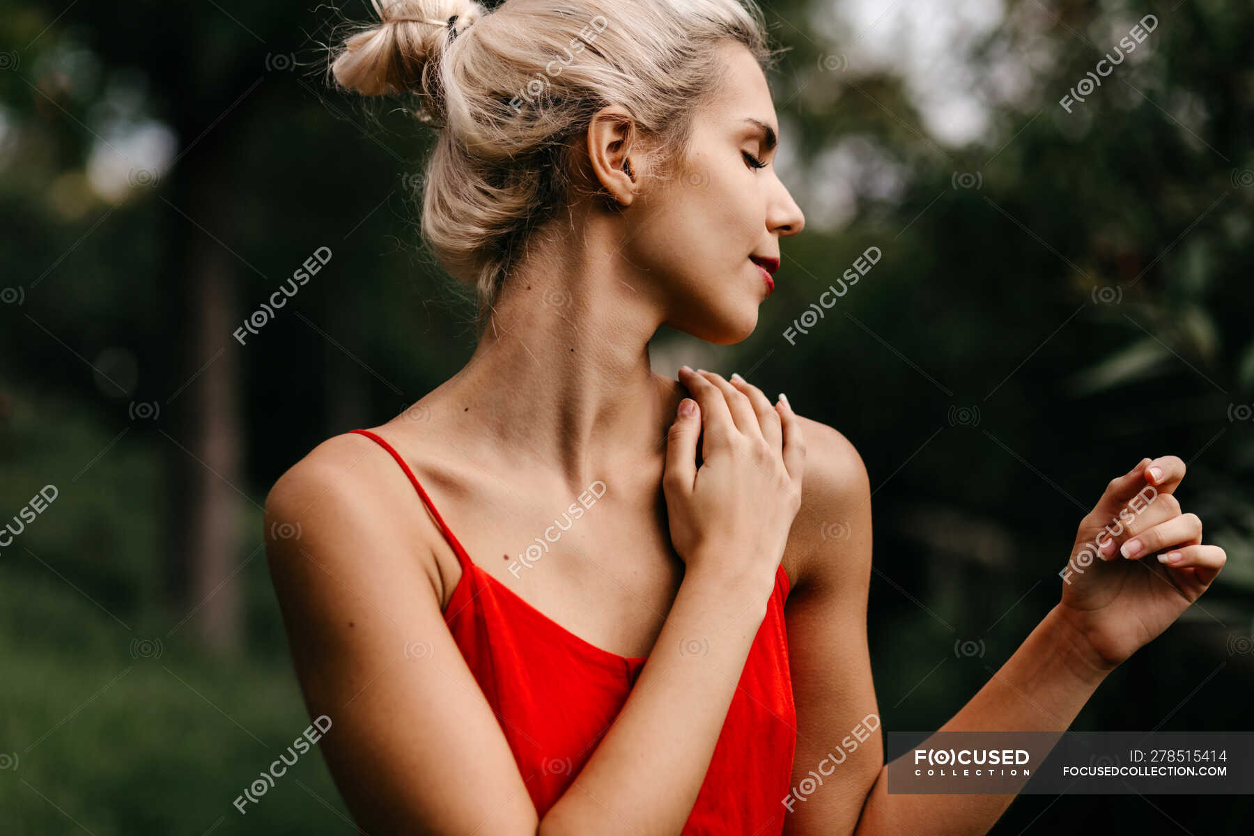 Side View Of Attractive Blonde Dressed In Red Sensually Posing And Touching Her Neck With Closed 