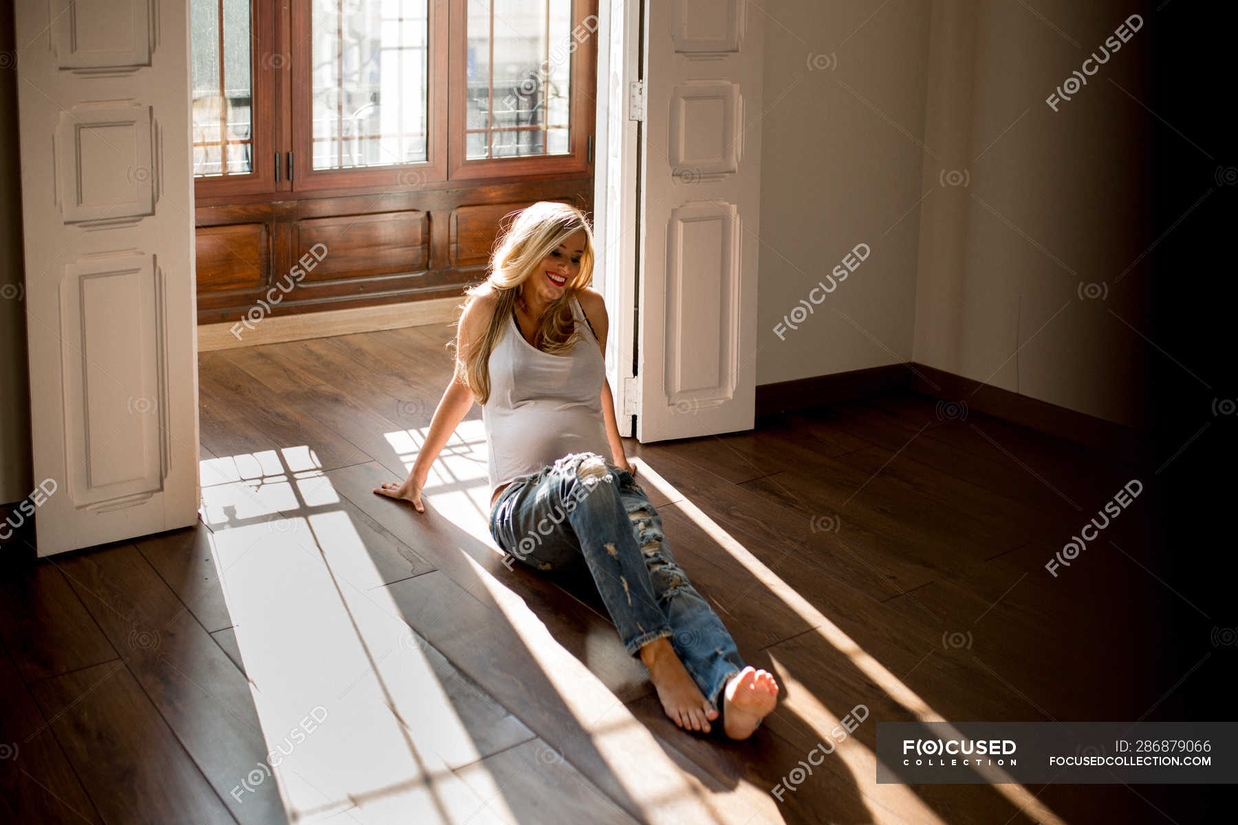 Happy Pregnant Woman Smiling And Looking Away While Sitting On
