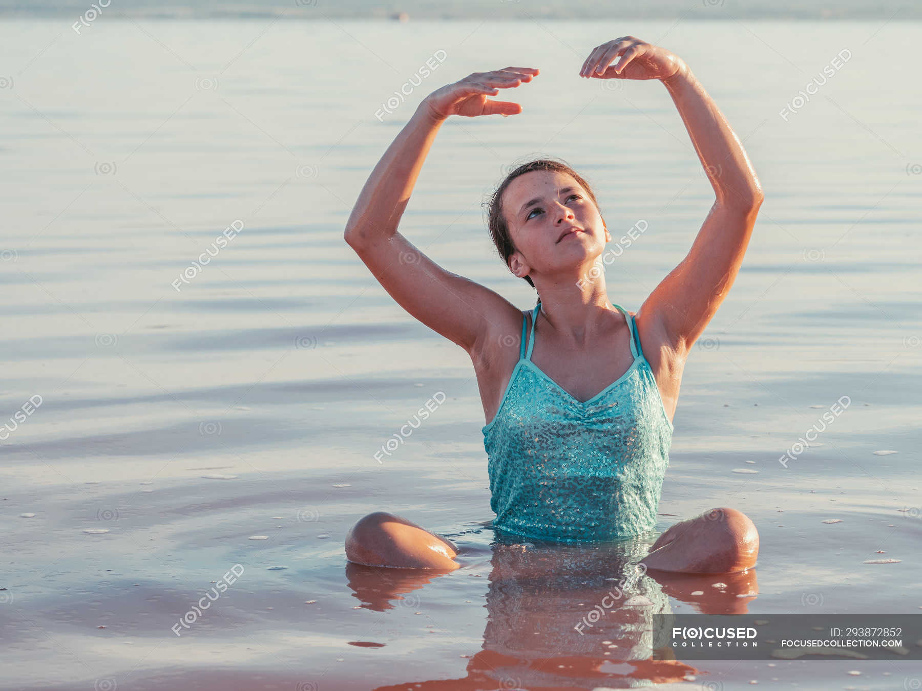 Thoughtful Girl Sitting In Water With Hands Up And Looking Up — Enjoying Lifestyle Stock