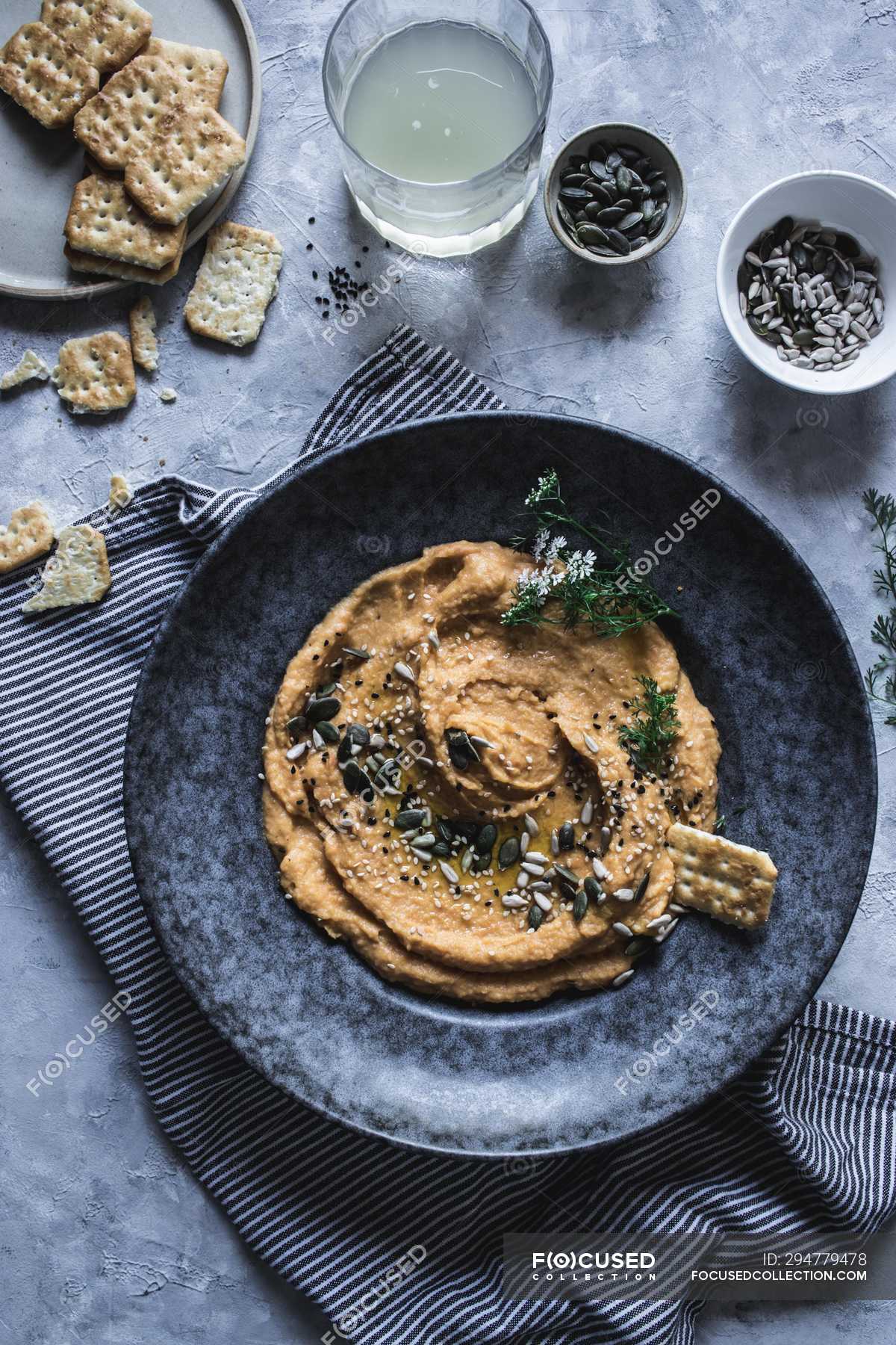 Top view of cracker in plate with carrot and chickpea hummus decorated