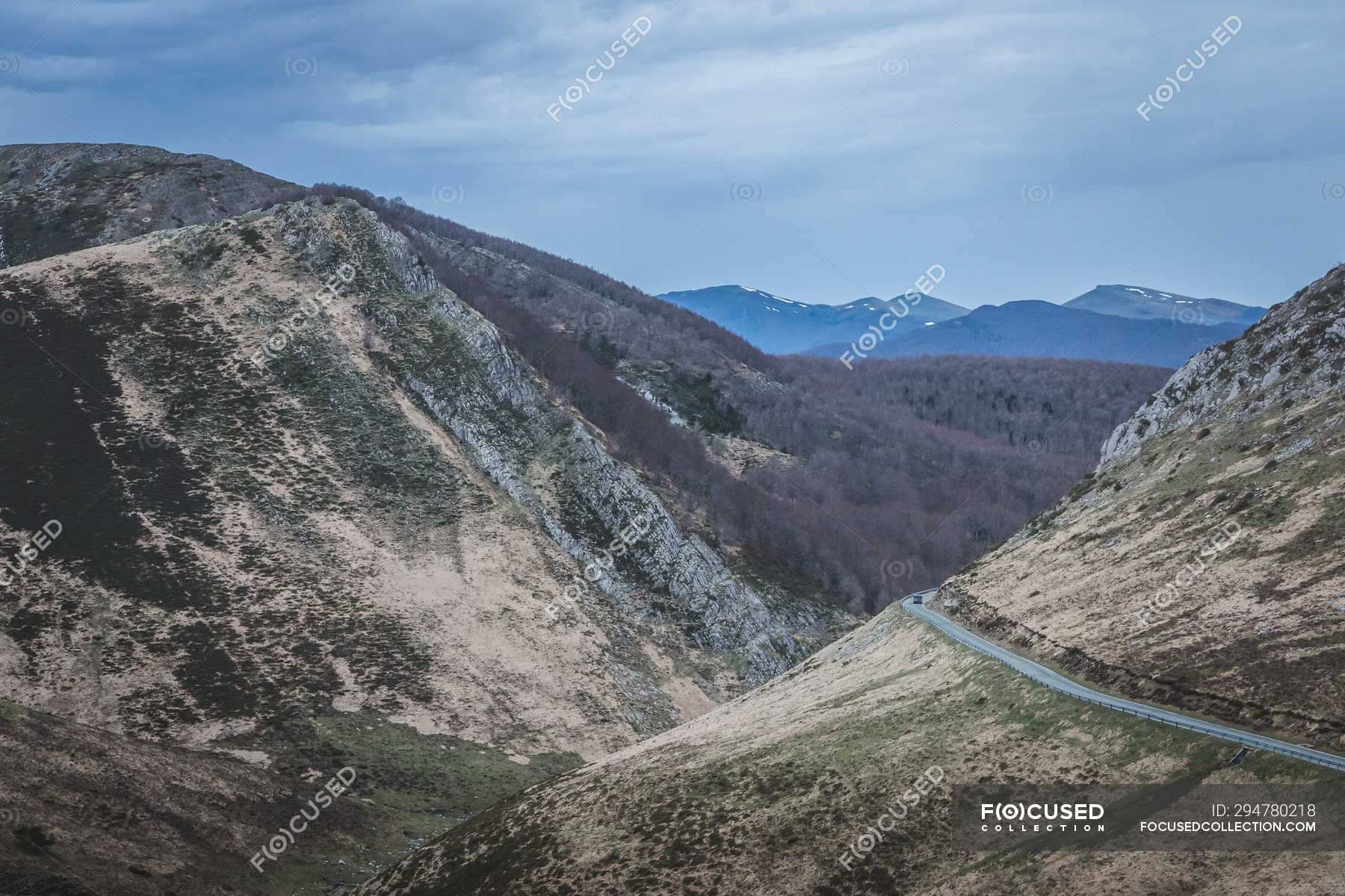 narrow-winding-road-going-on-slopes-of-grassy-hills-on-cloudy-day-in