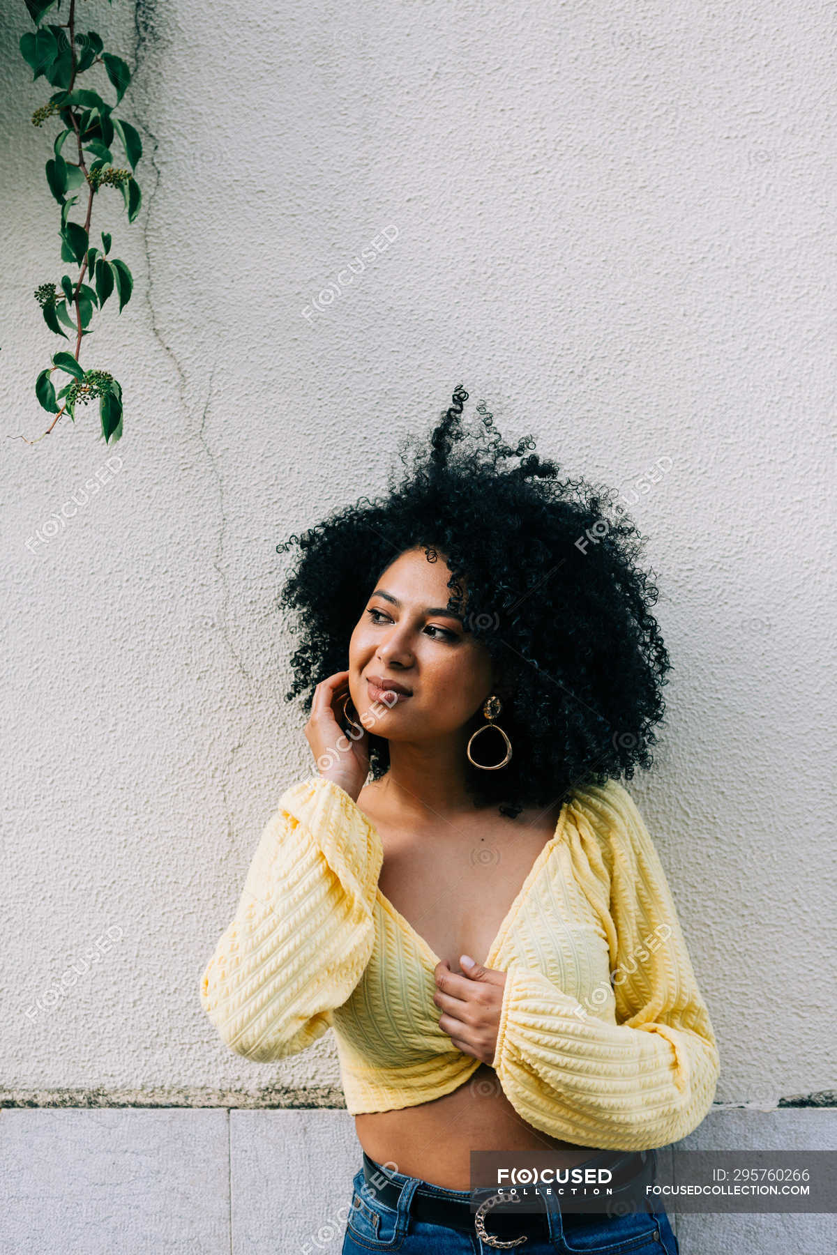 Pretty ethnic woman in yellow crop top with black curly hair looking away  on street — stylish, hairstyle - Stock Photo | #295760266