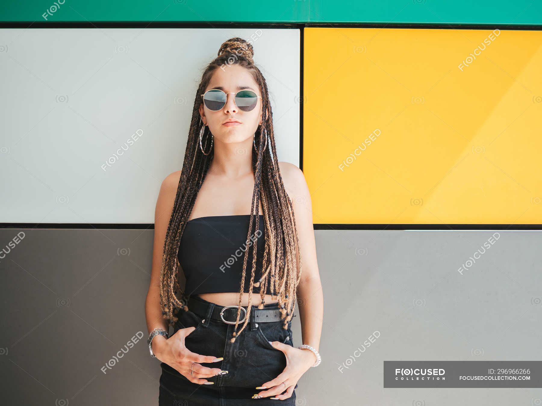 Pretty stylish teenage girl with hands in pockets and unique dreadlocks ...