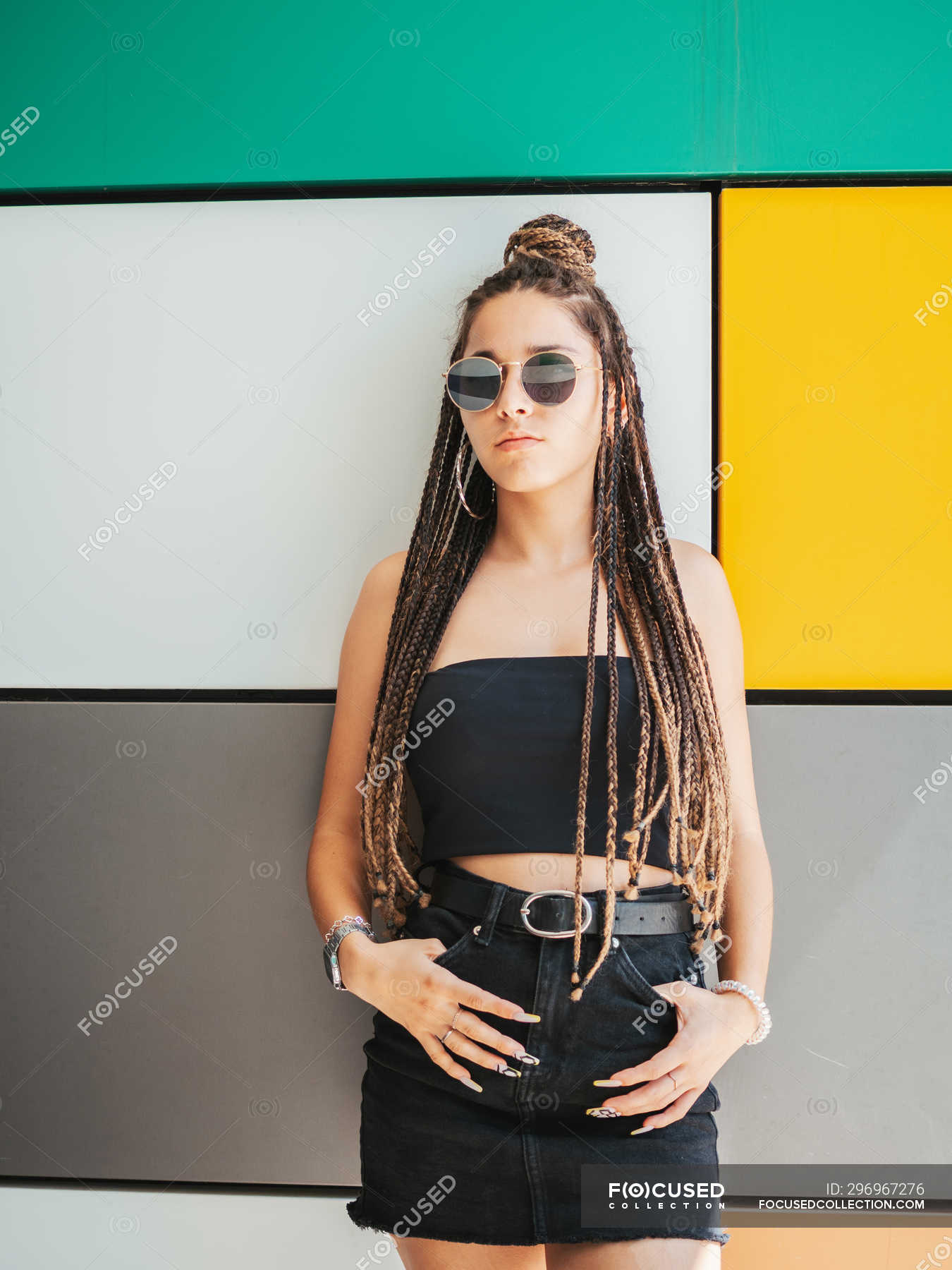 Pretty stylish teenage girl with hands in pockets and unique dreadlocks ...