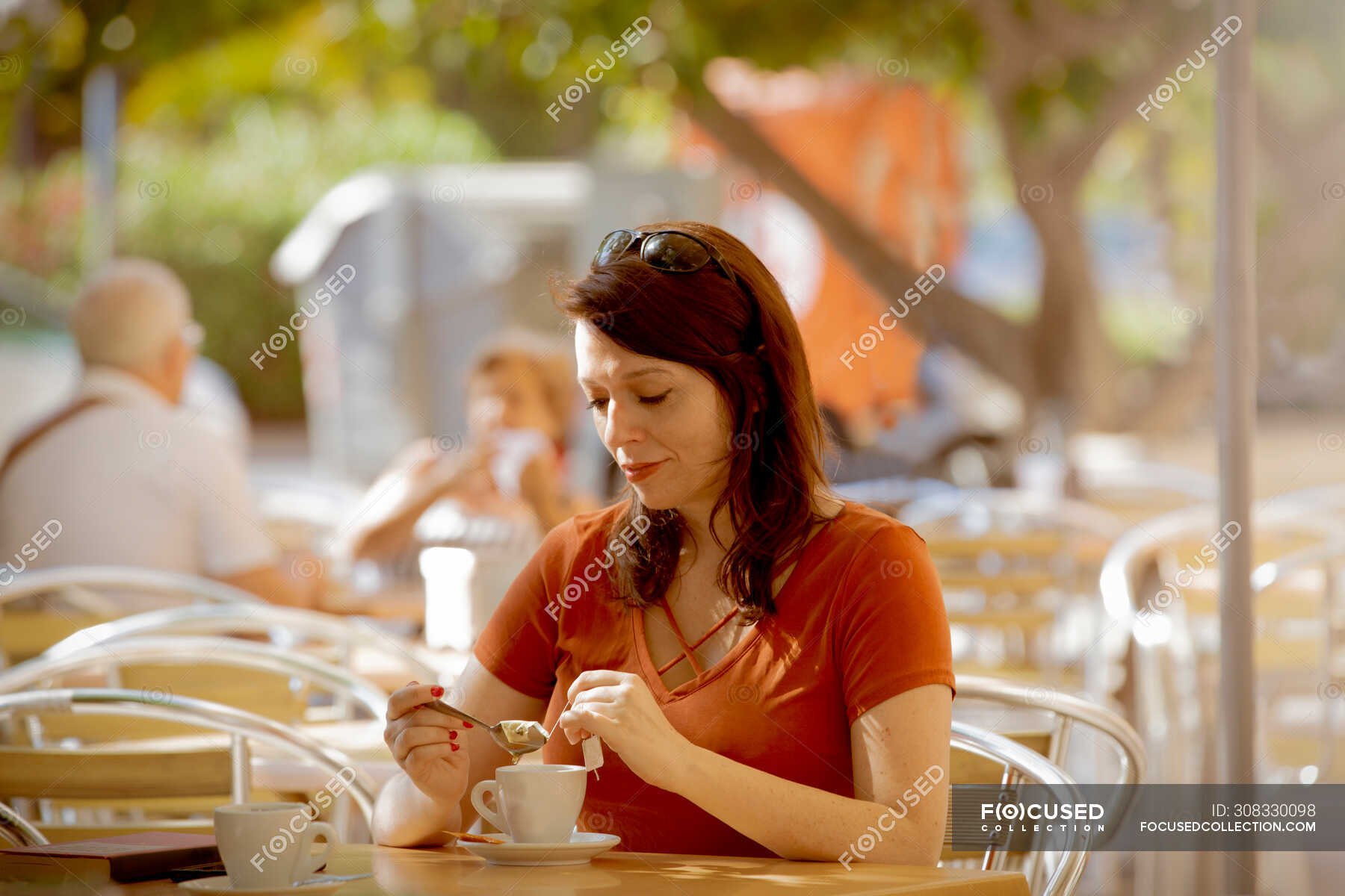 Casual relaxed lady making tea while sitting on cozy summer cafe ...