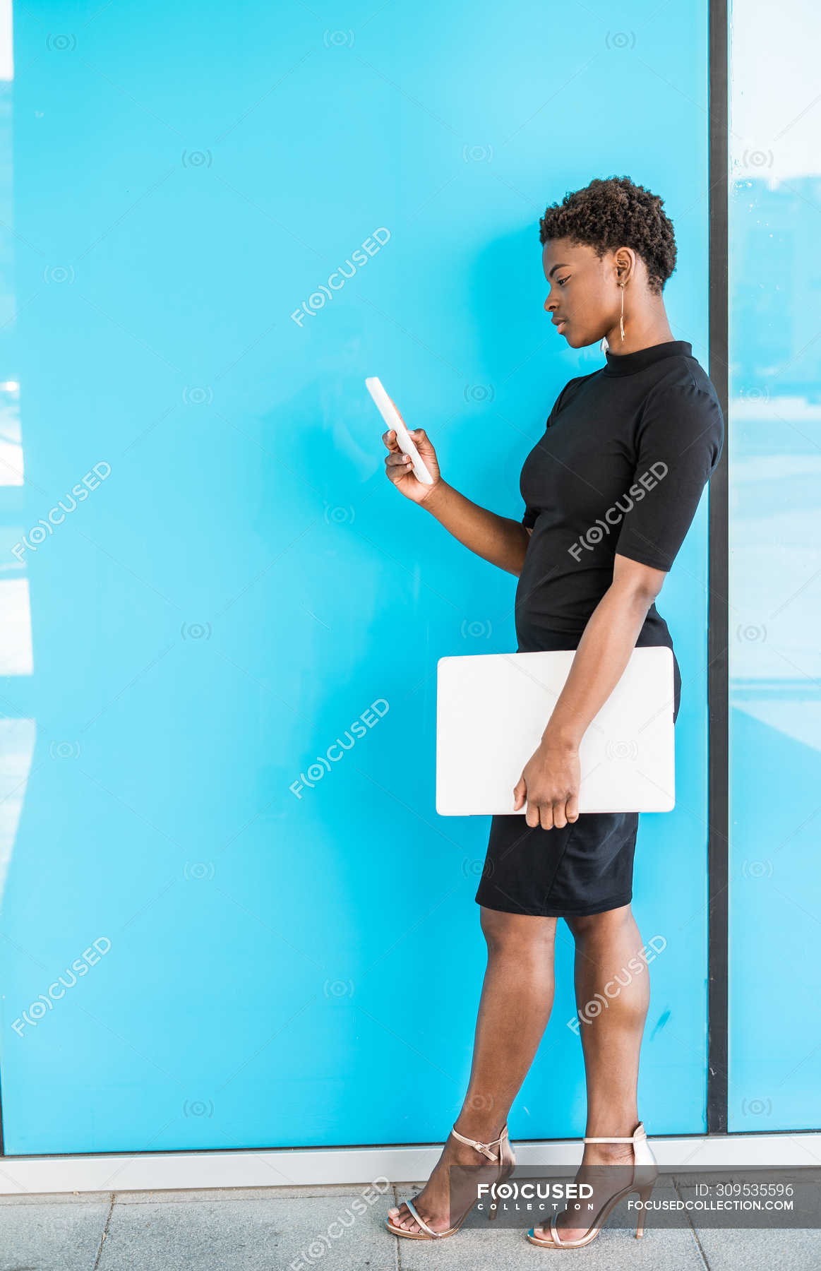 cool-african-american-smart-woman-using-mobile-phone-holding-laptop