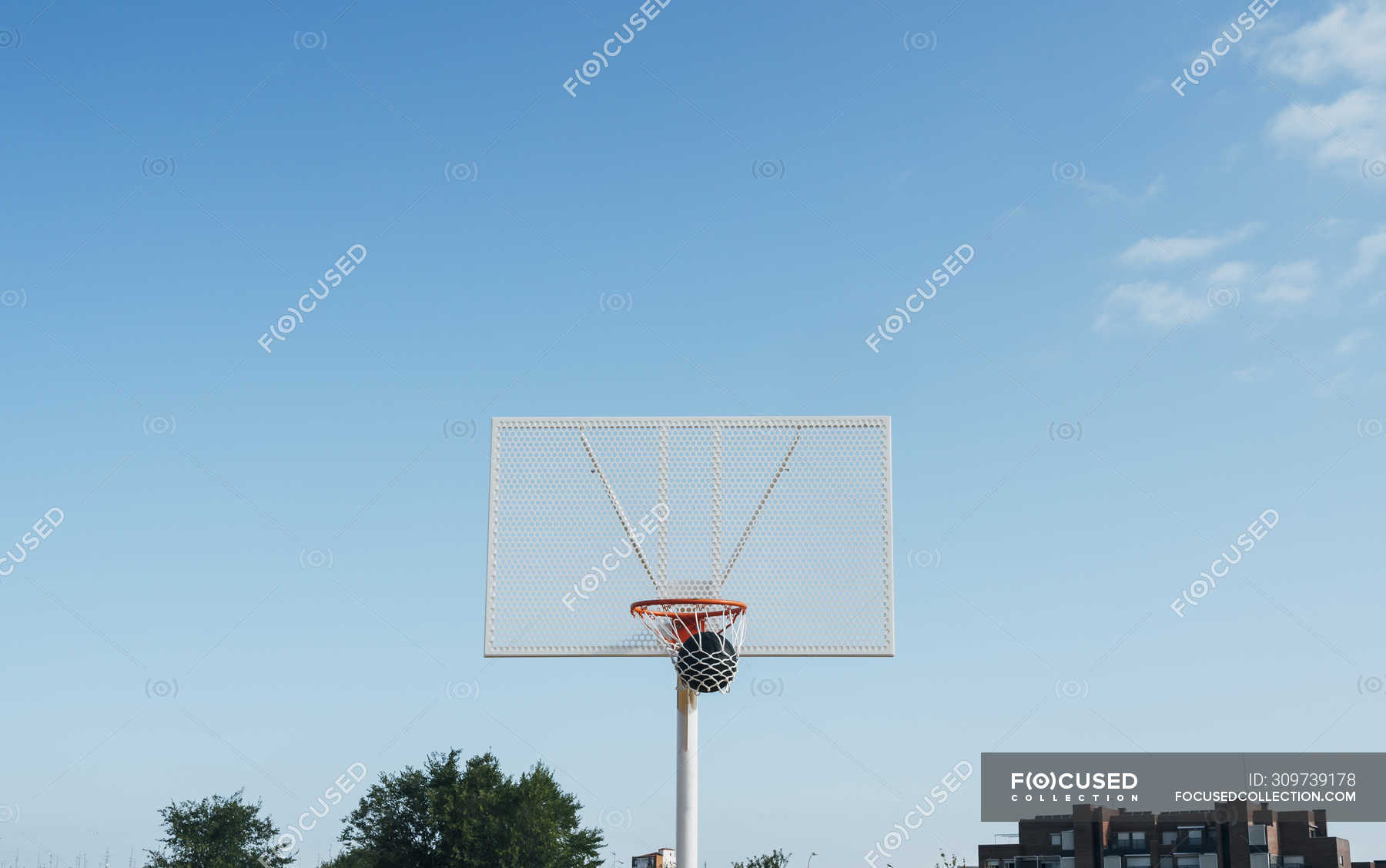 Ball into net basket in outdoor basketball court. — from below