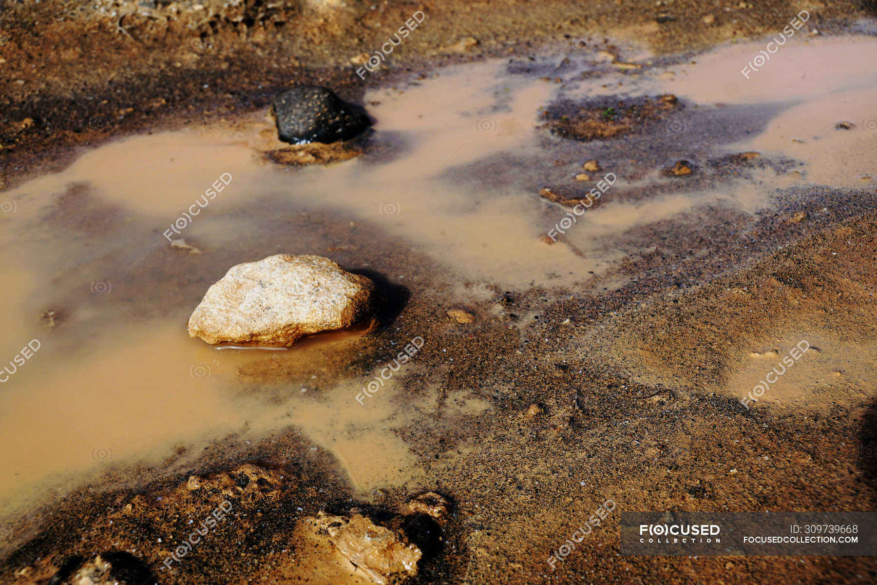 From above swamp with turbid muddy water brown soil and black rocks