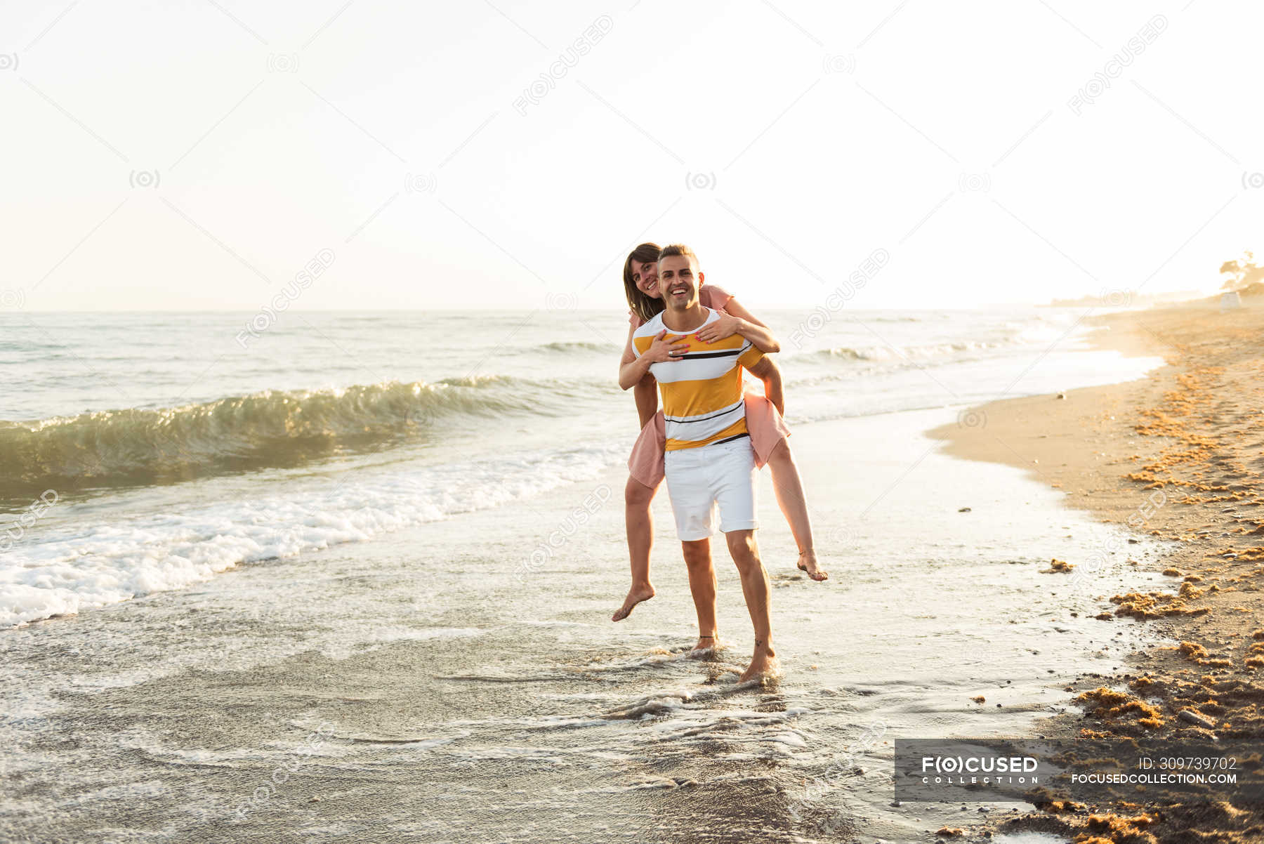 Full length cheerful male giving piggyback ride to smiling female on ...