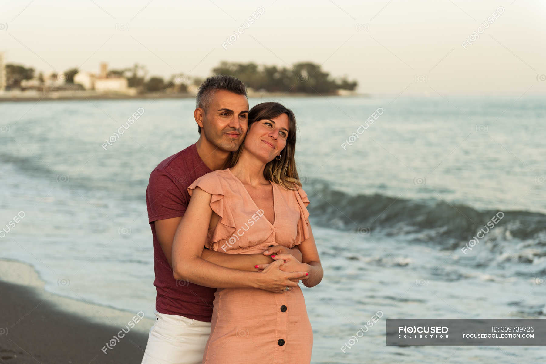 Adult Man Hugging Woman From Behind And Looking Away While Standing On 