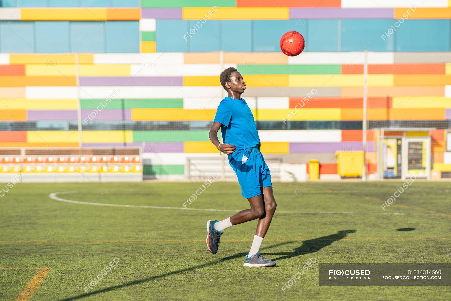 Ethnic male athlete juggling football ball on sport field — soccer