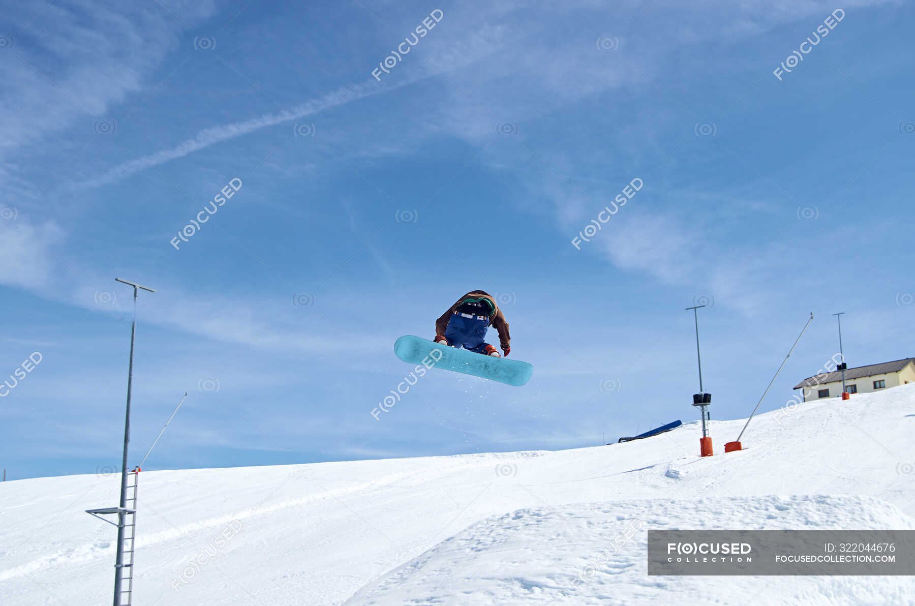 Unrecognizable snowboarder jumping on slope — from below, action Stock Photo 322044676