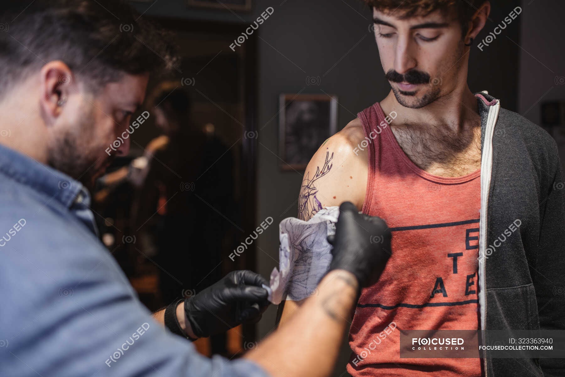 tattoo-master-removing-template-on-client-s-forearm-paper-body