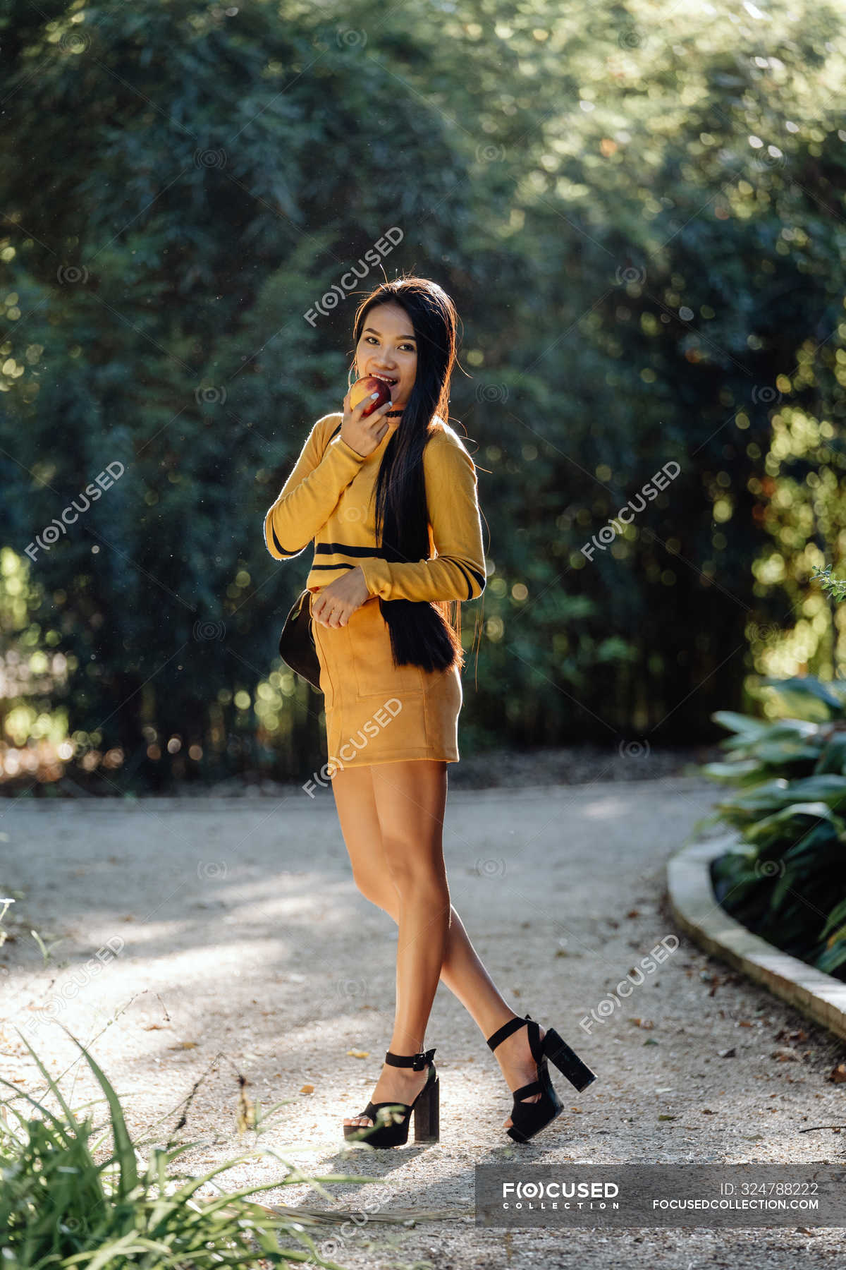 Graceful Long Haired Brunette Asian Woman With Apple In Sunlight On