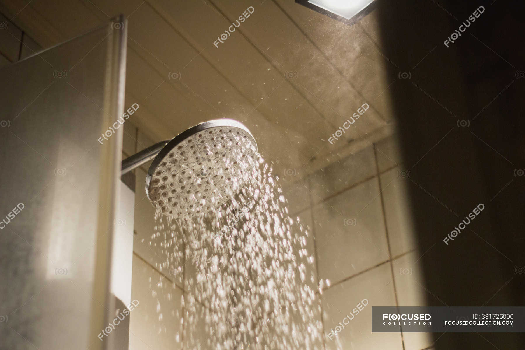 From below of shower head with hot water drops flowing in bathroom of