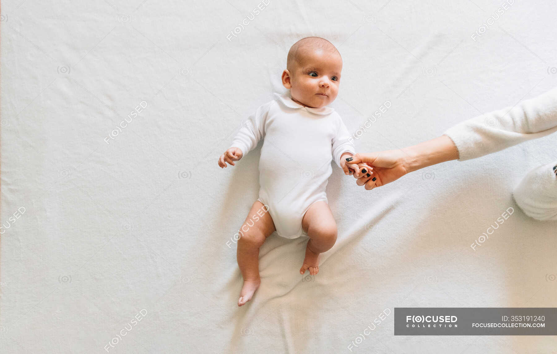 Vista dall'alto della donna senza volto che tocca le mani del neonato gioioso con la bocca Vista dall'alto della donna senza volto che tocca le mani del neonato gioioso con la bocca