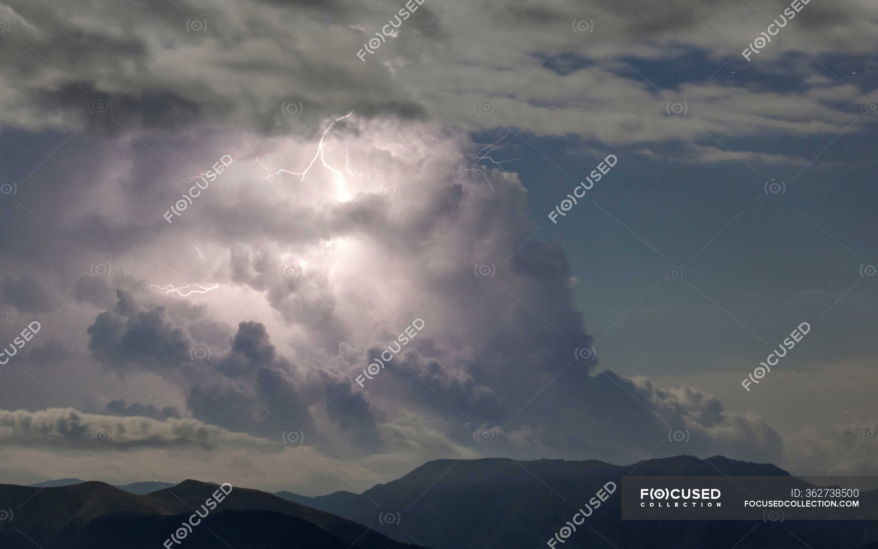 Thunder clouds with lightning on blue sky over dark rocky mountain range —  overcast, magnificent - Stock Photo | #362738500