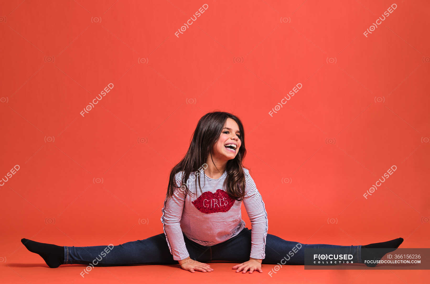 Happy Preteen Girl Gymnast In Trendy Clothes Looking Away While Sitting With Leg Stretched Out 