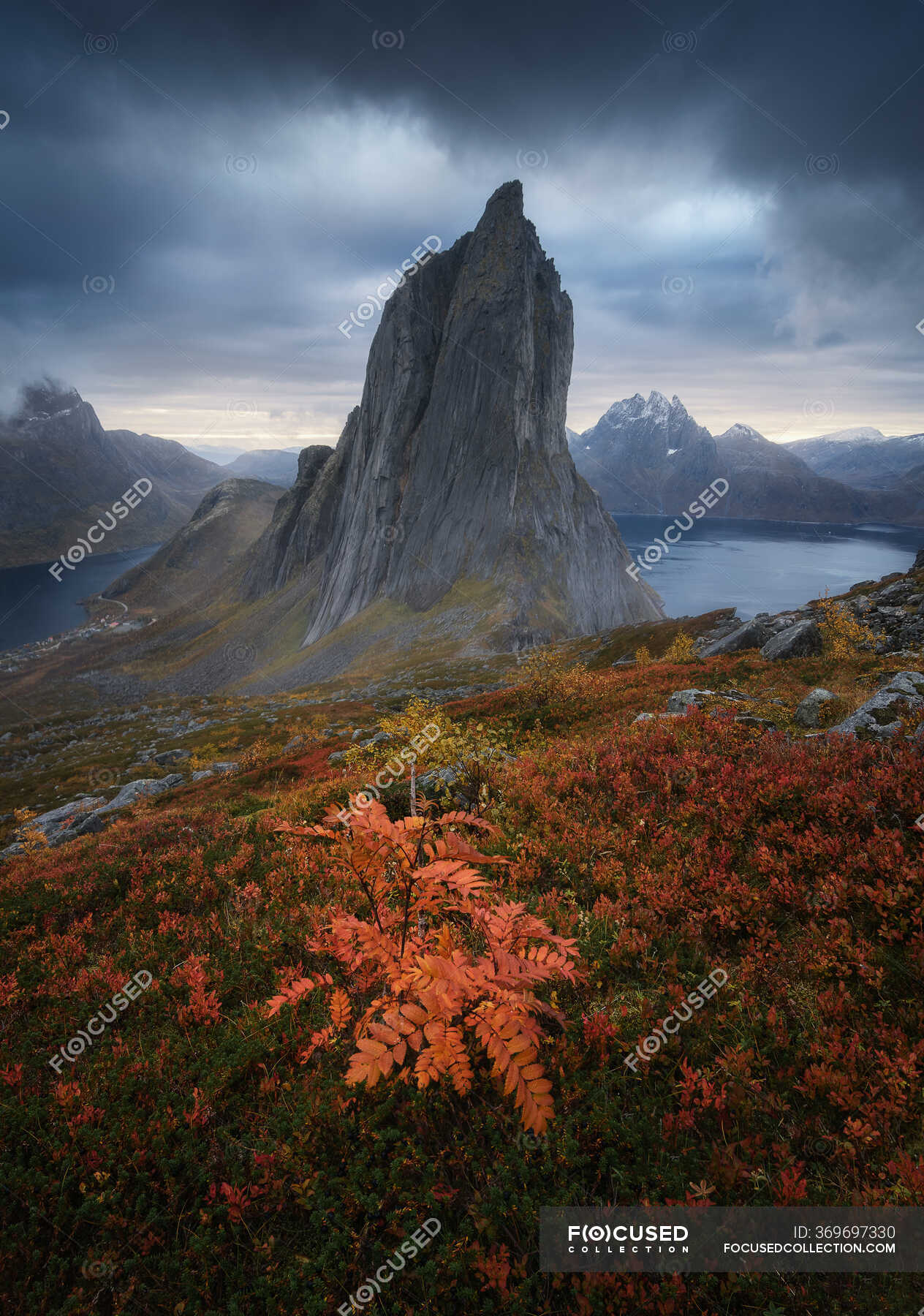 Segla Mountain Located In Grassy Valley Near Calm Basin Against Dark Overcast Sky On Island Of Senja Norway Dull Rock Stock Photo