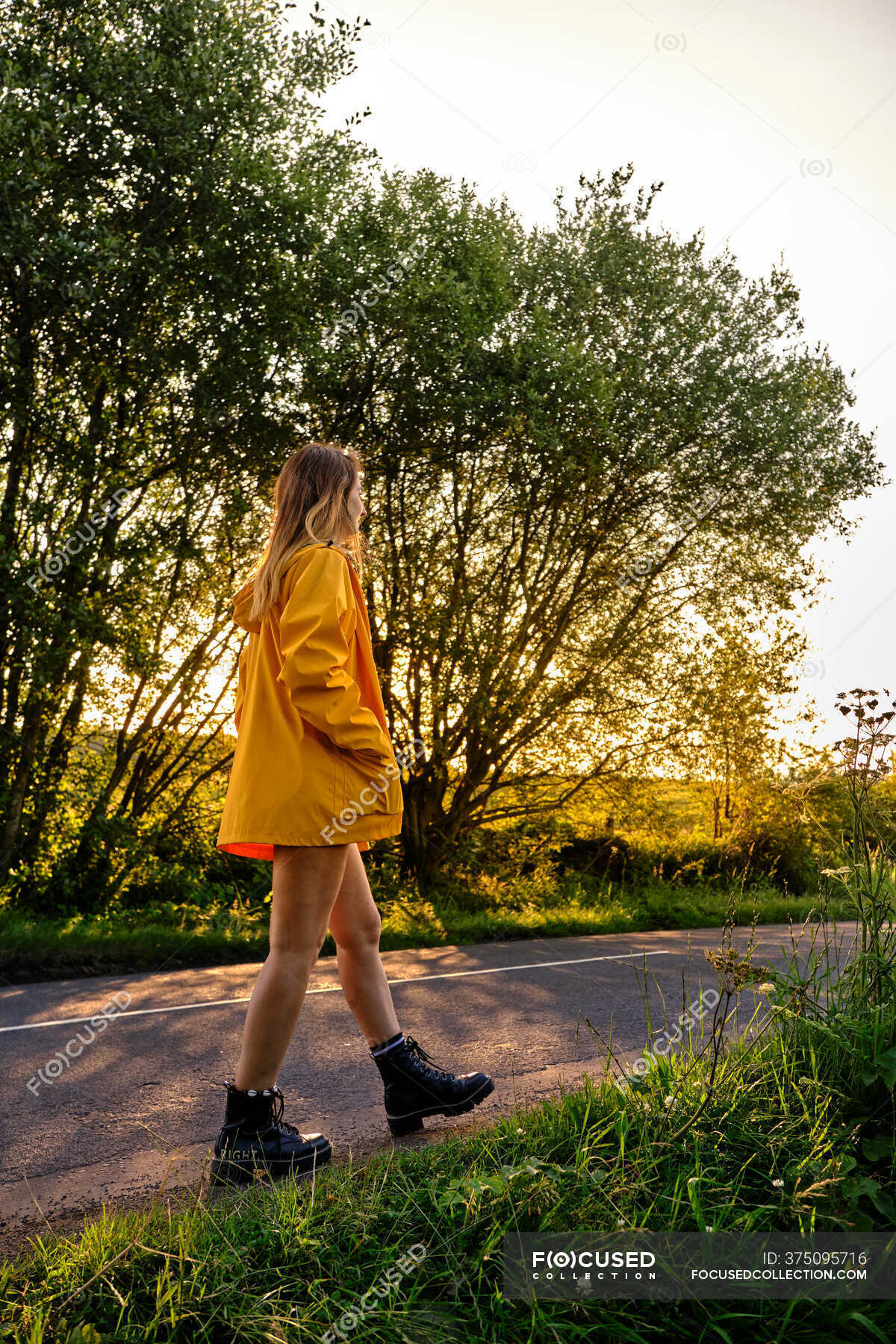 Side view of female in casual outfit with hands in pocket strolling on ...