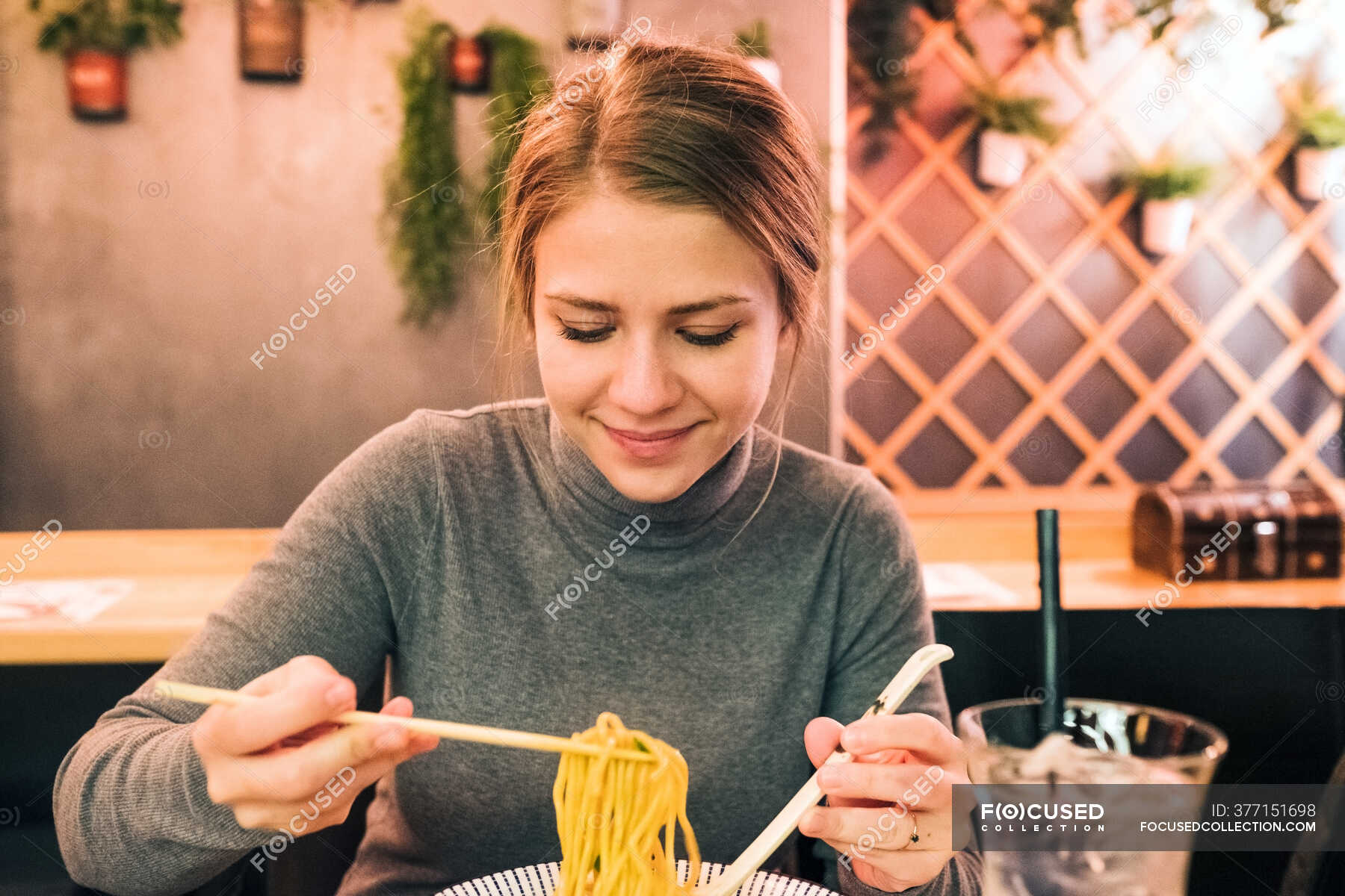 Eating tradition. Eating traditions. Weekend overeating. Сидит по-турецки и ест палочками.