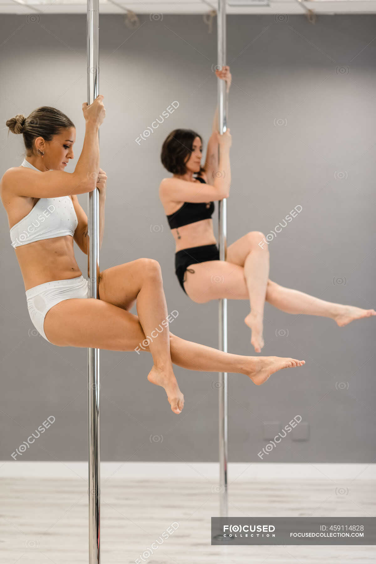 Side view of young strong female athletes doing vertical pose while dancing  on metal poles in studio — barefoot, dance - Stock Photo | #459114828