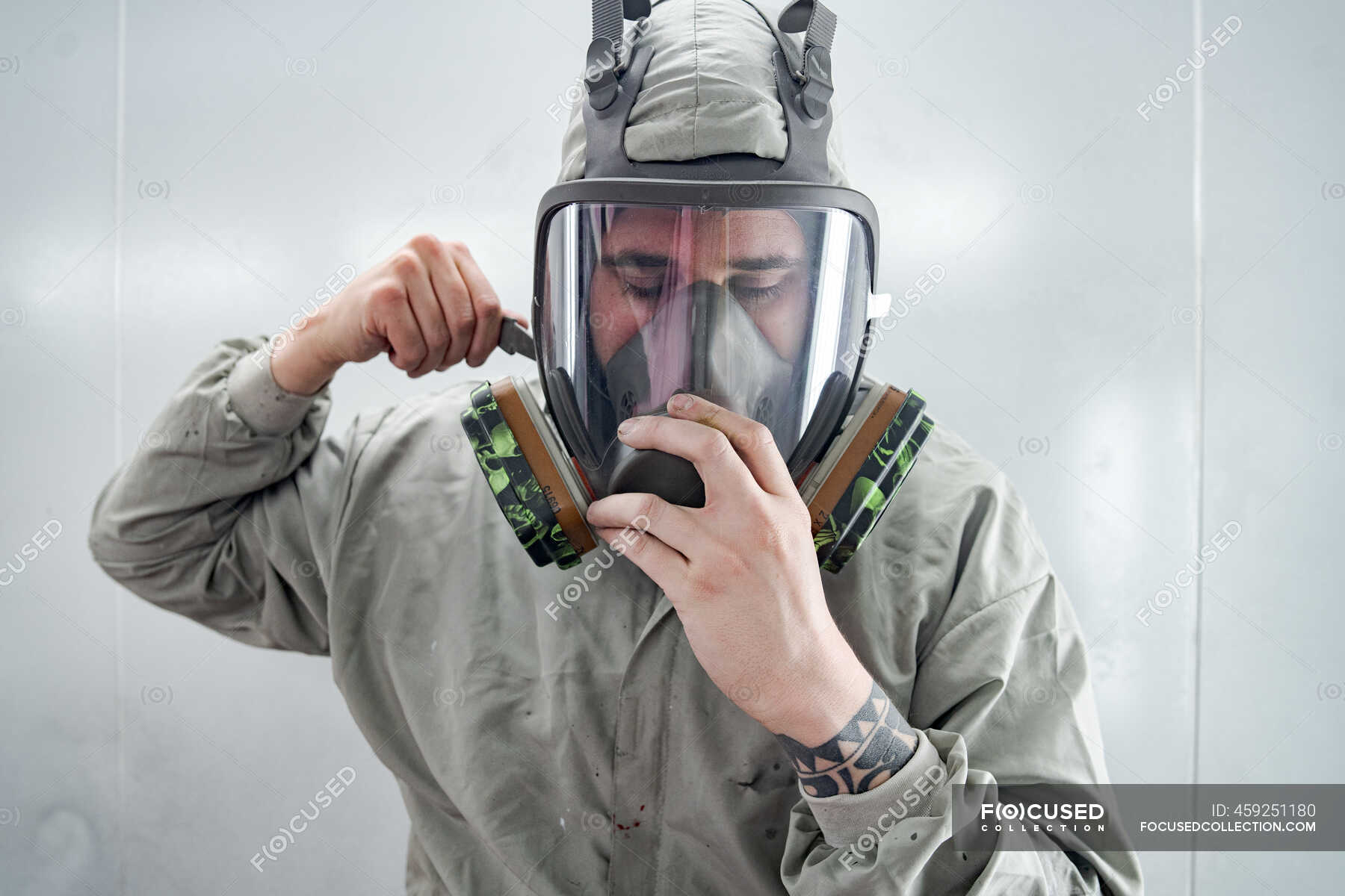 Male mechanic putting on respirator and protective suit while preparing ...