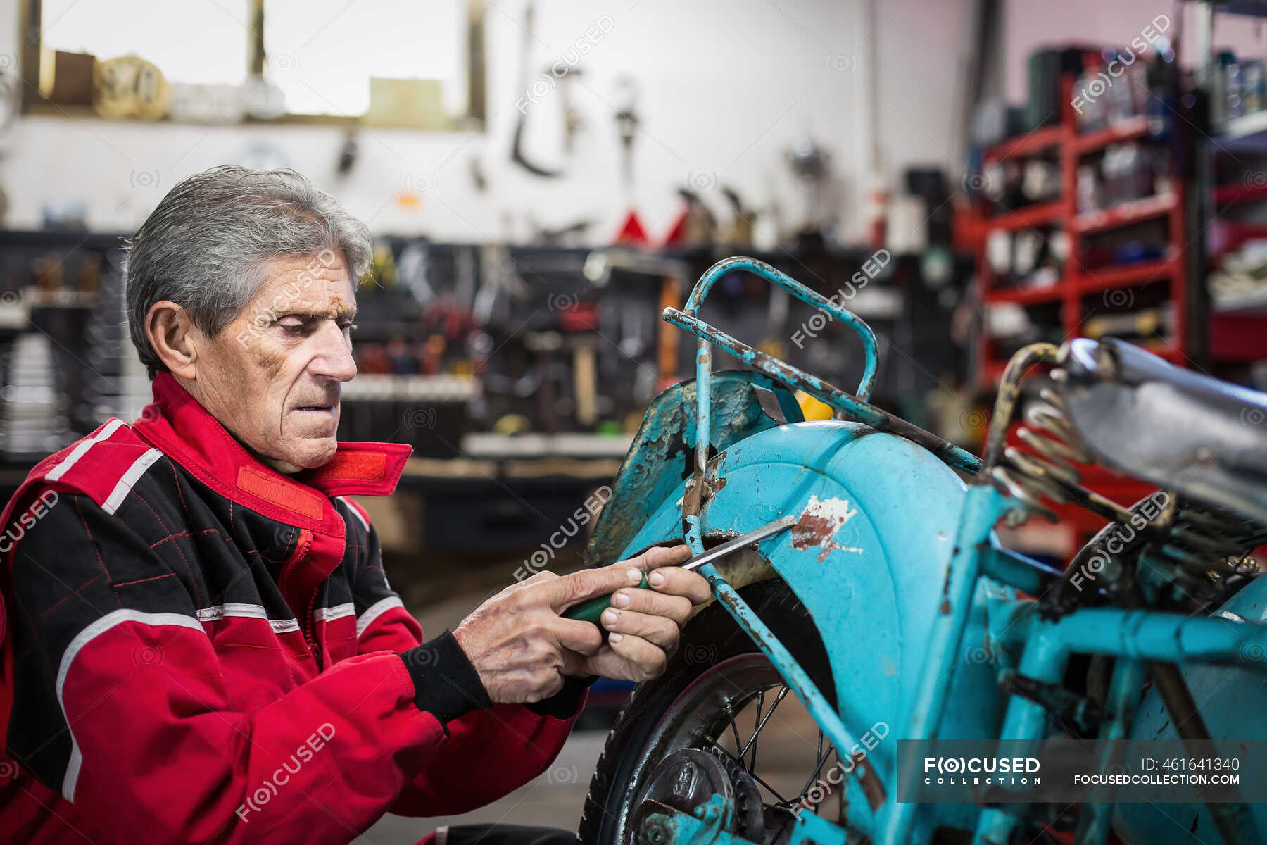 Side view of elderly gray haired male mechanic with screwdriver ...