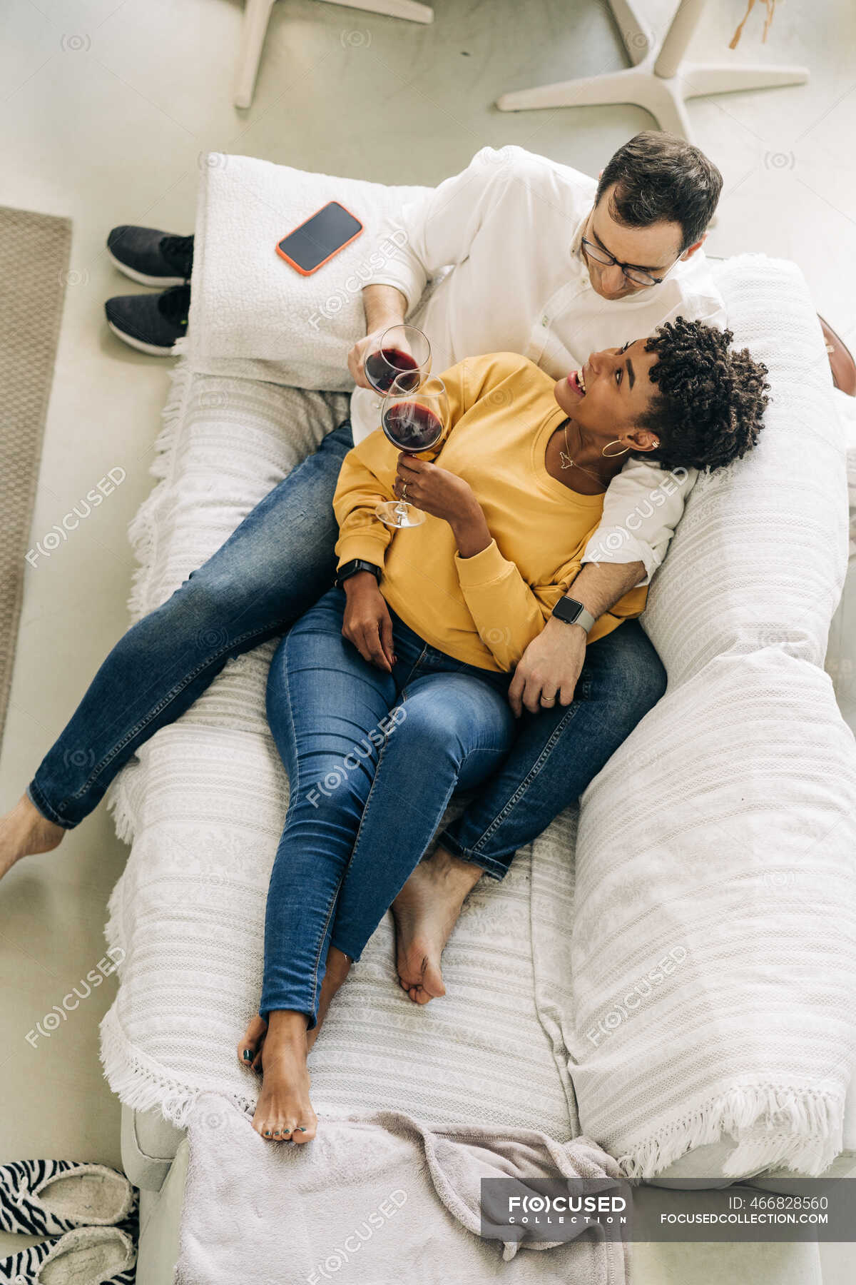 Content Multiracial Couple Chilling On Sofa At Home With Red Wine In