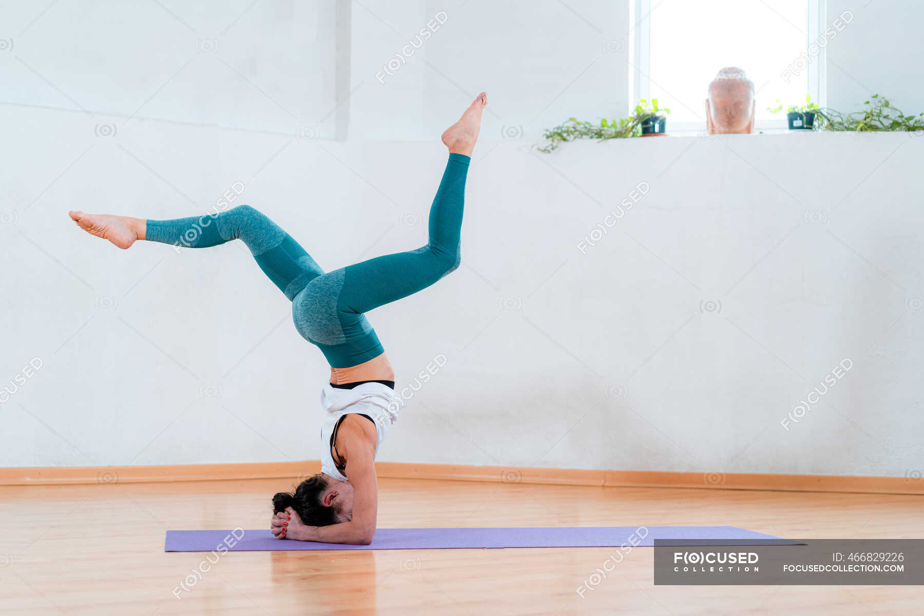 Side View Of Anonymous Flexible Female In Sportswear Standing On Head 