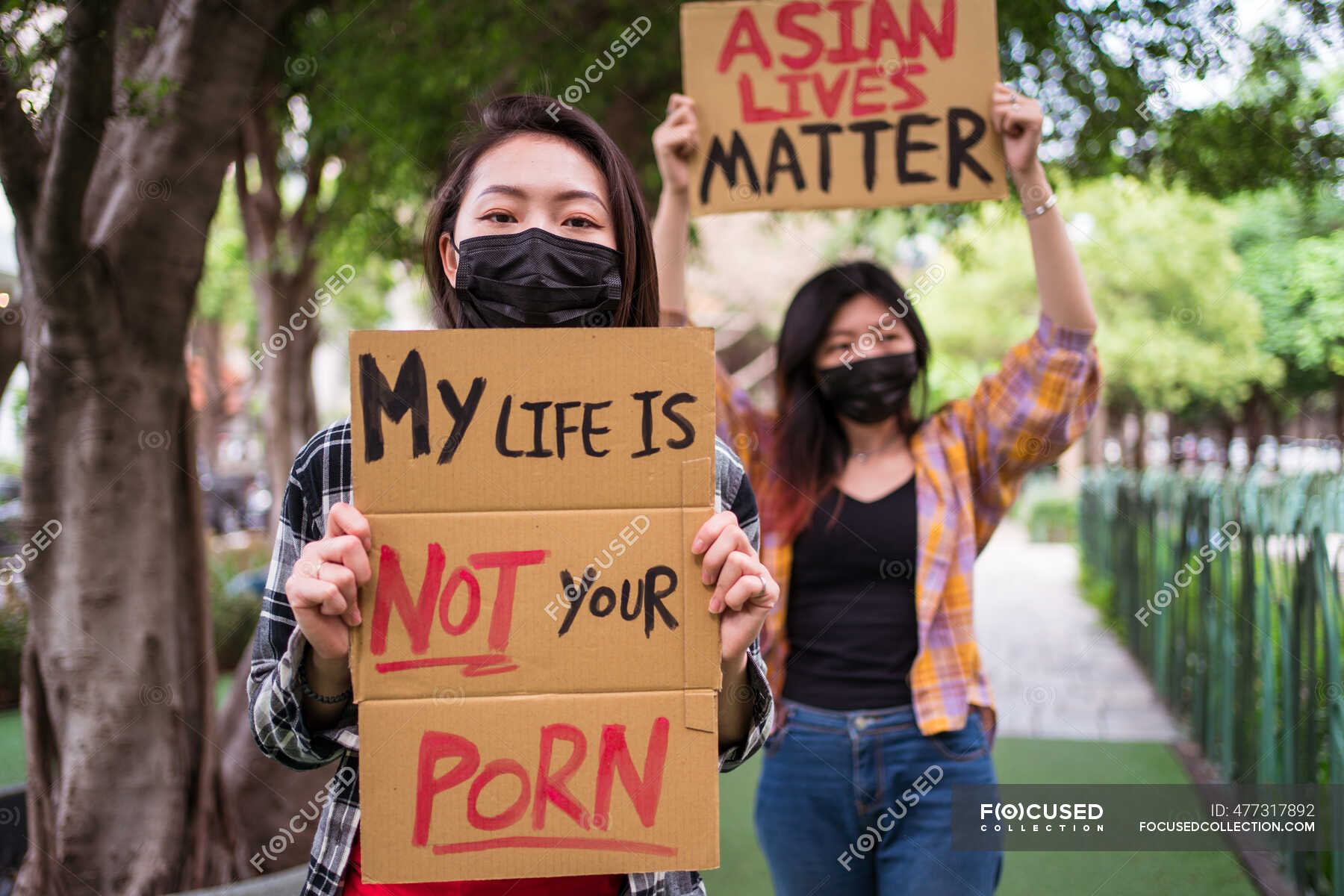 Ethnic females in masks holding posters protesting against racism in city  street and looking at camera â€” inscription, protester - Stock Photo |  #477317892