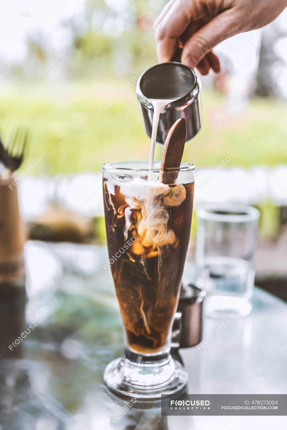 Crop unrecognizable barista pouring fresh milk from pitcher into glass of  cold black coffee served on glass table in outdoor cafeteria — liquid,  anonymous - Stock Photo | #478273004
