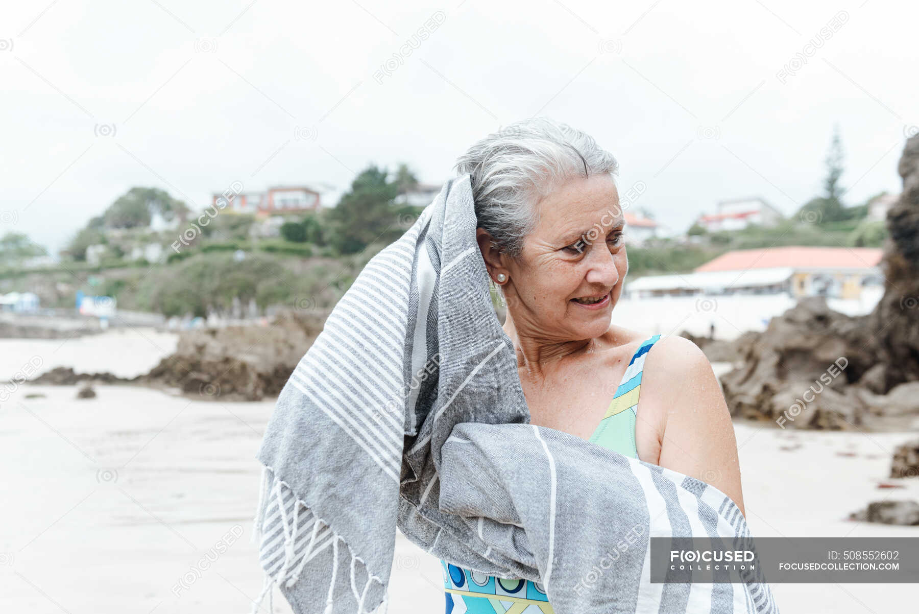 positive-aged-female-in-swimwear-wiping-wet-hair-with-towel-after