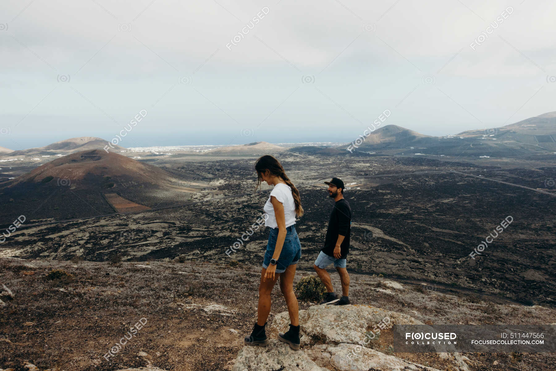 Side View Of Young Couple Of Travelers Walking On Hill And Enjoying