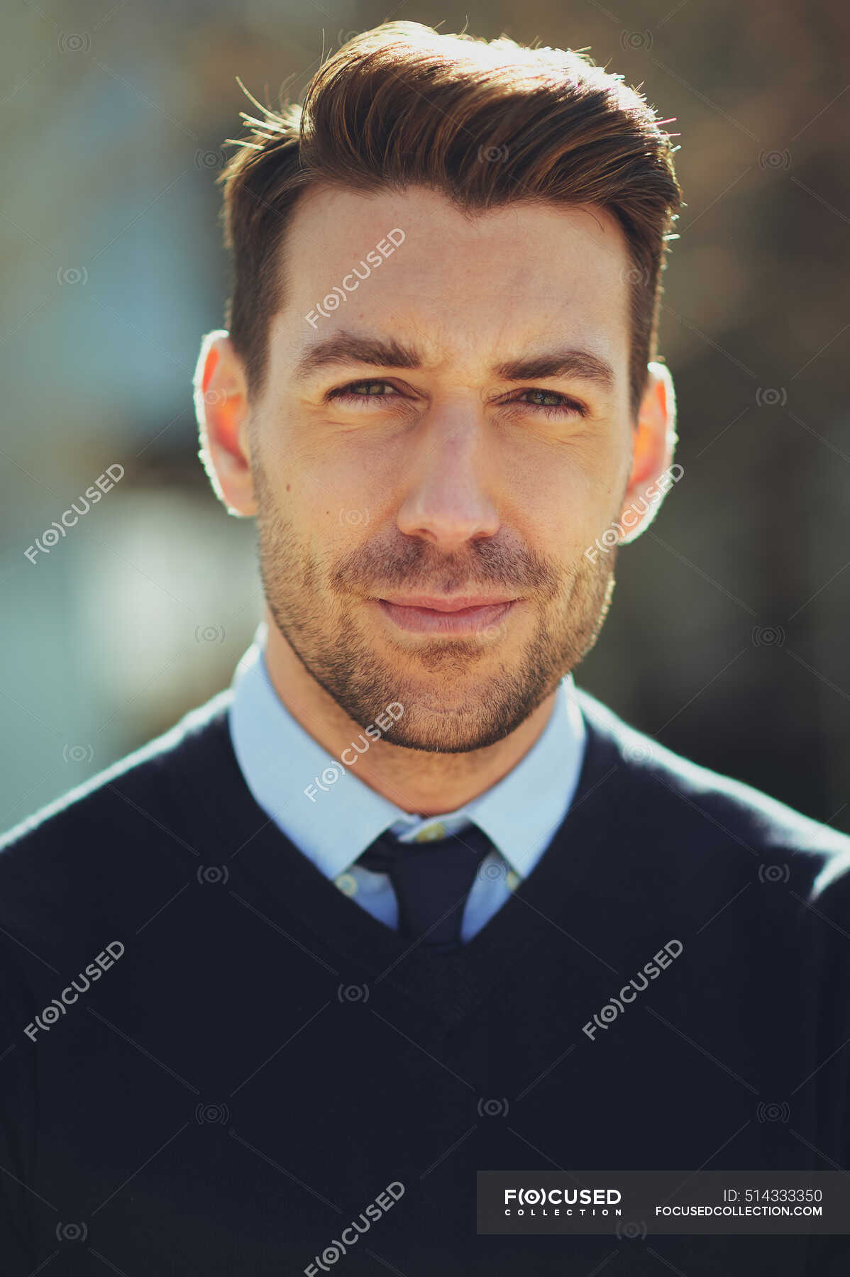 Bearded male entrepreneur with modern haircut looking at camera in town ...