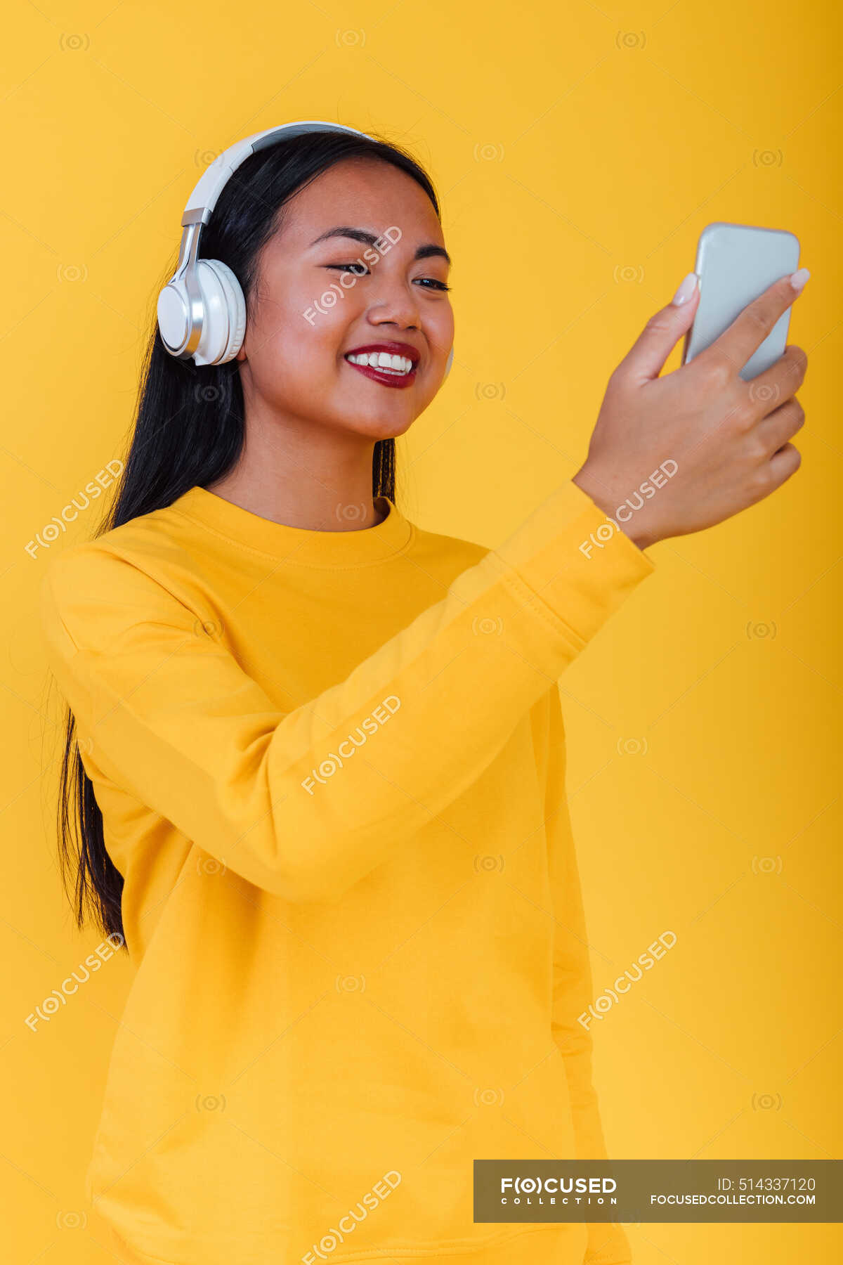 content-asian-female-listening-to-music-in-headphones-and-taking-self