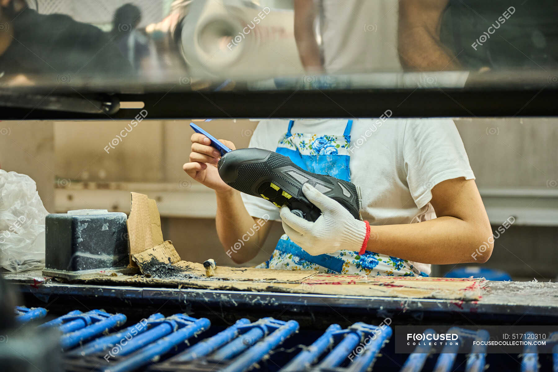 Particolare di lavoro che applica colla alla suola delle scarpe in una  linea di produzione di calzature cinesi Foto stock - Alamy