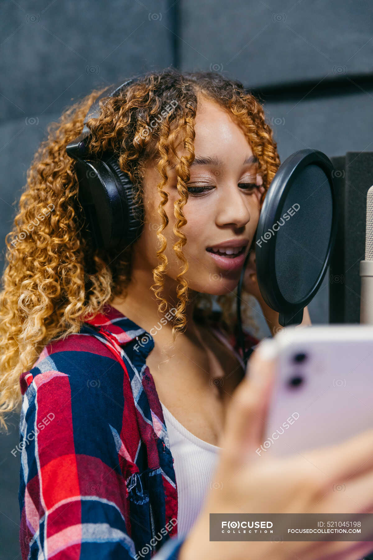 cheerful-african-american-female-singer-in-headphones-with-smartphone