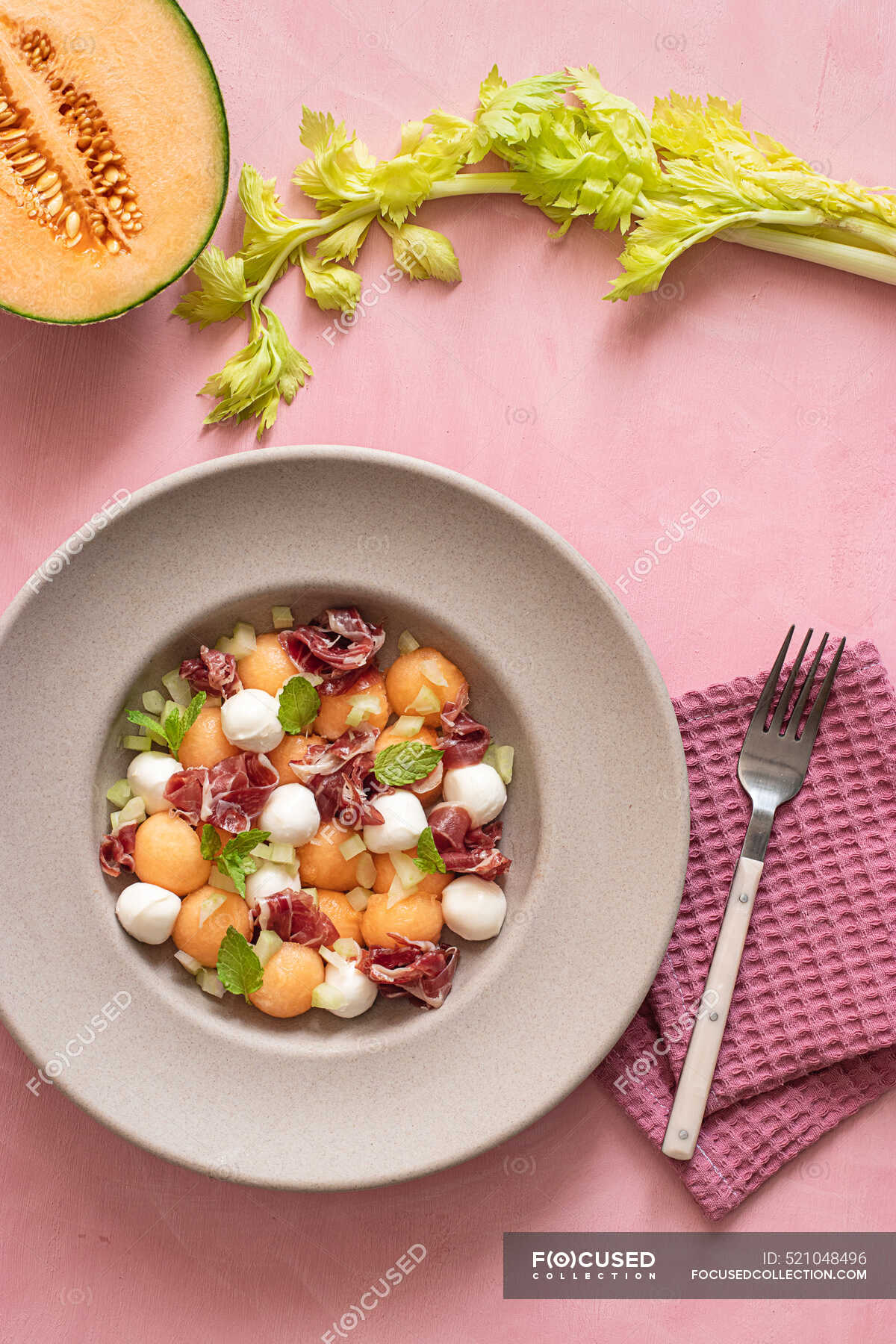 From above exotic melon, mozzarella and prosciutto salad on pink