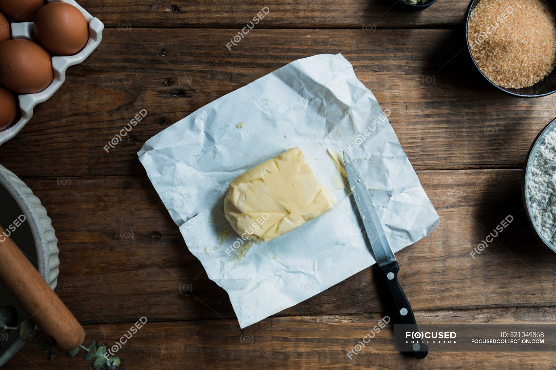 Knife ready to cut piece of butter on a pastry preparation on wooden